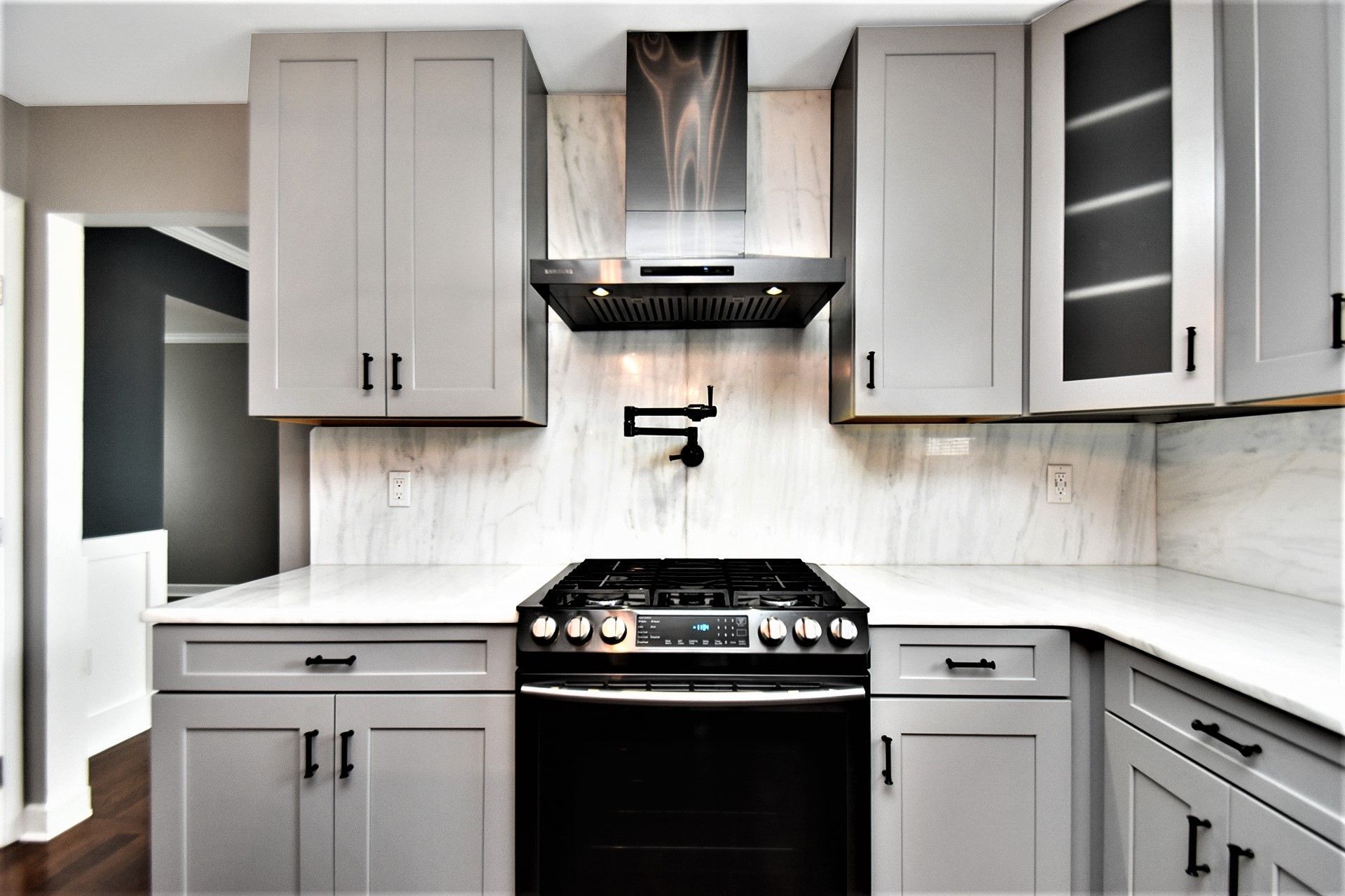 A kitchen with gray cabinets , a stove , and a sink.