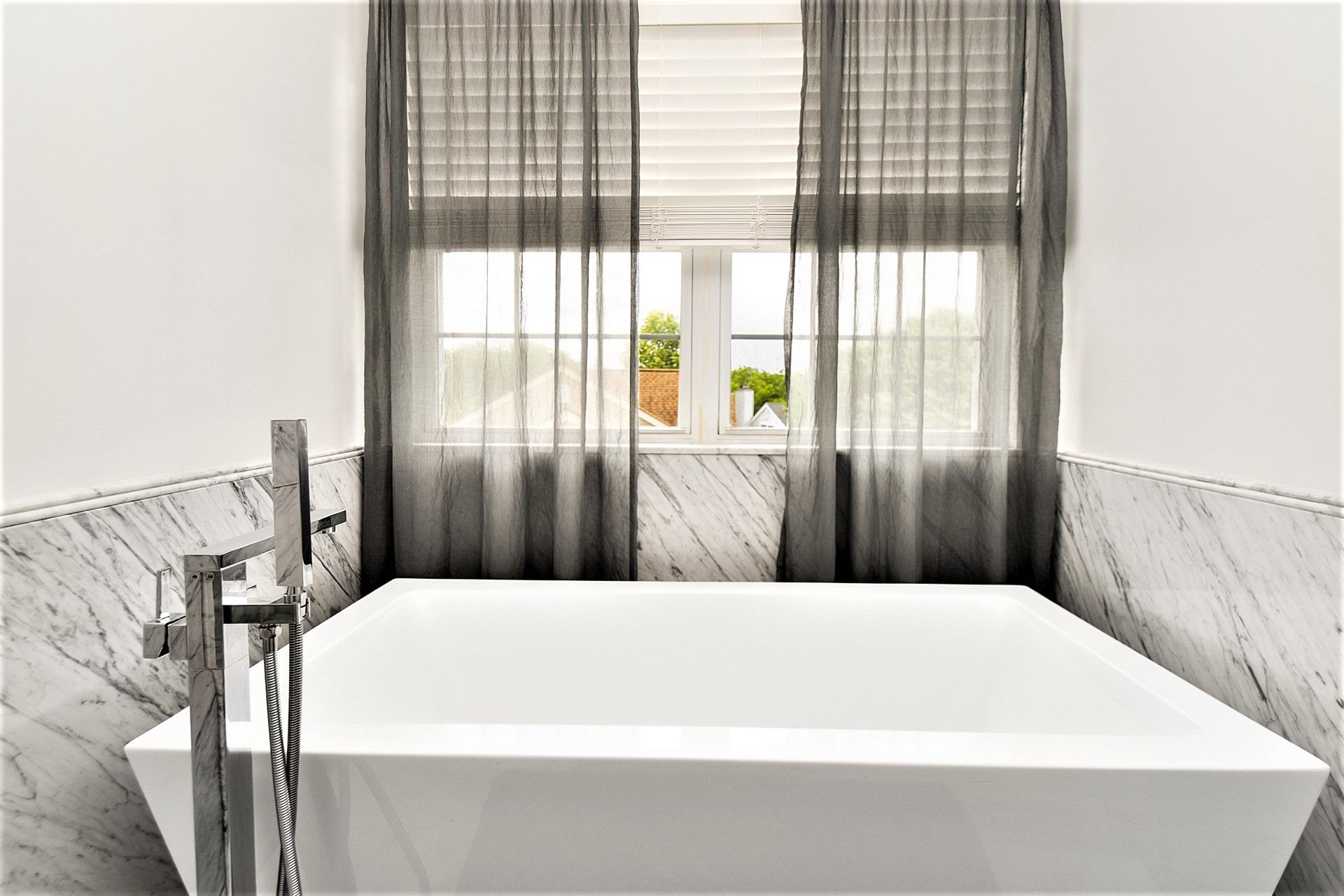 A bathroom with a large bathtub and a window.