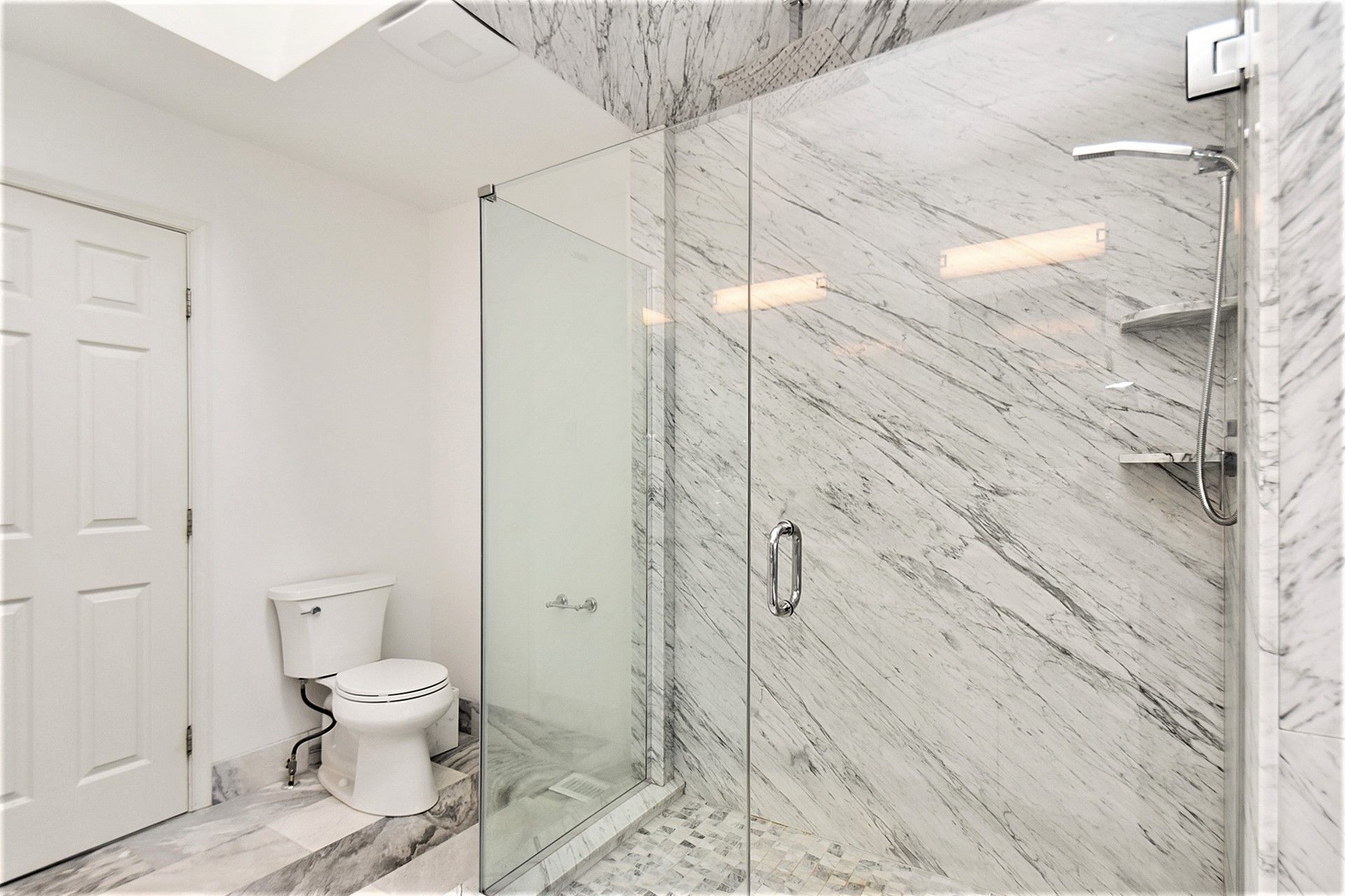 A bathroom with a toilet and a walk in shower.