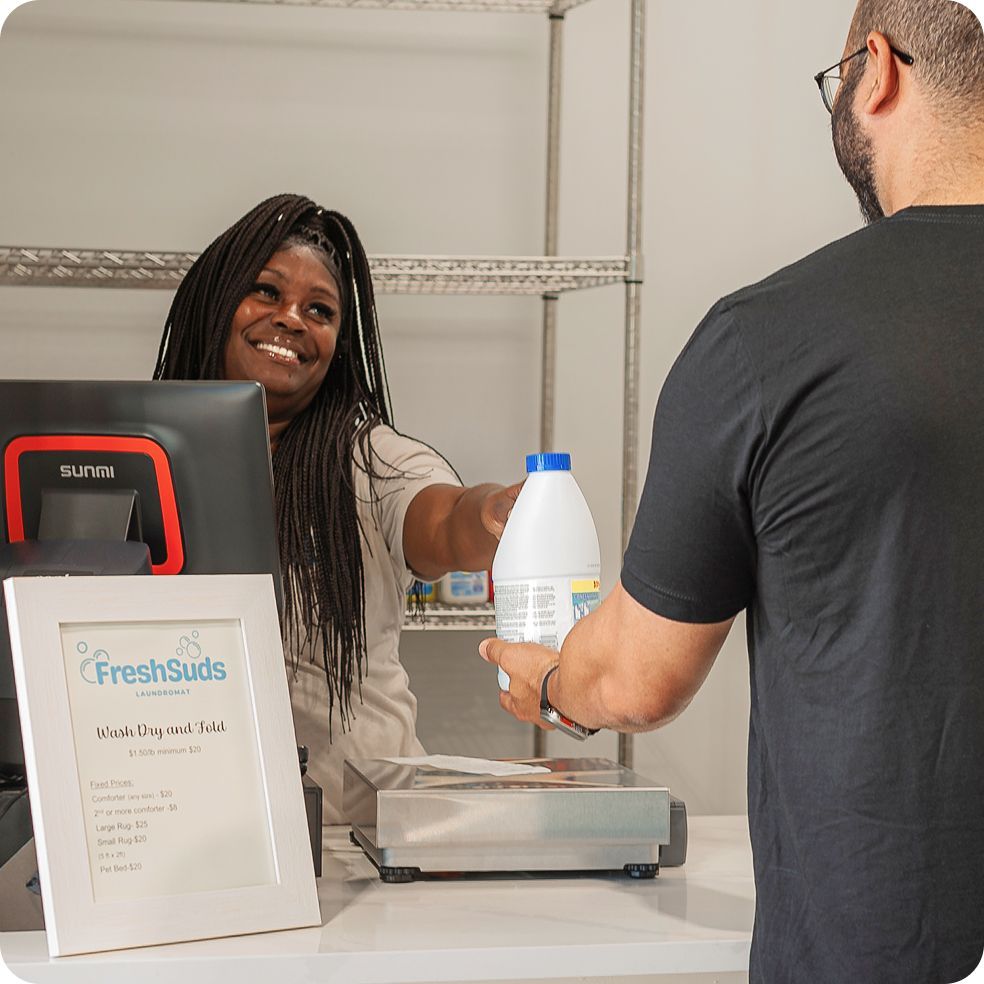 Stack of folded laundry, Tide detergent, and a laundromat sign. Fresh Suds Laundromat Memphis TN.