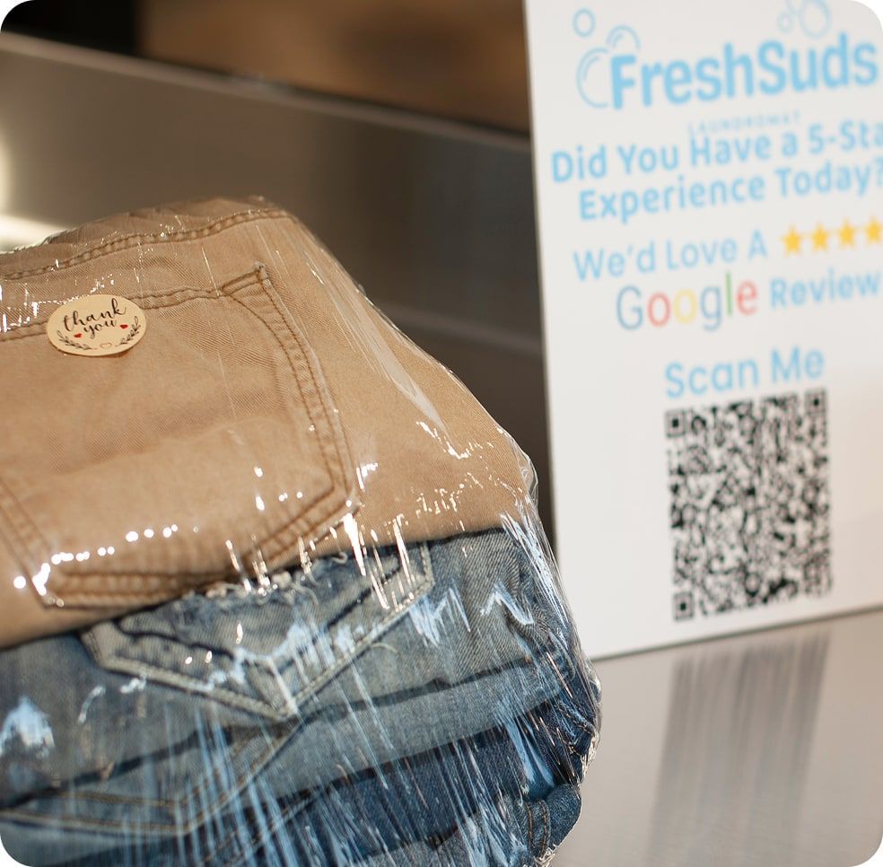 Stack of folded laundry, Tide detergent, and a laundromat sign. Fresh Suds Laundromat Memphis TN.