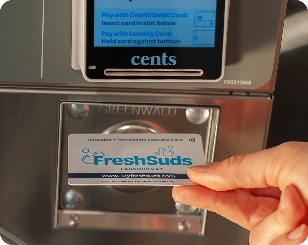 Stack of folded laundry, Tide detergent, and a laundromat sign. Fresh Suds Laundromat Memphis TN.