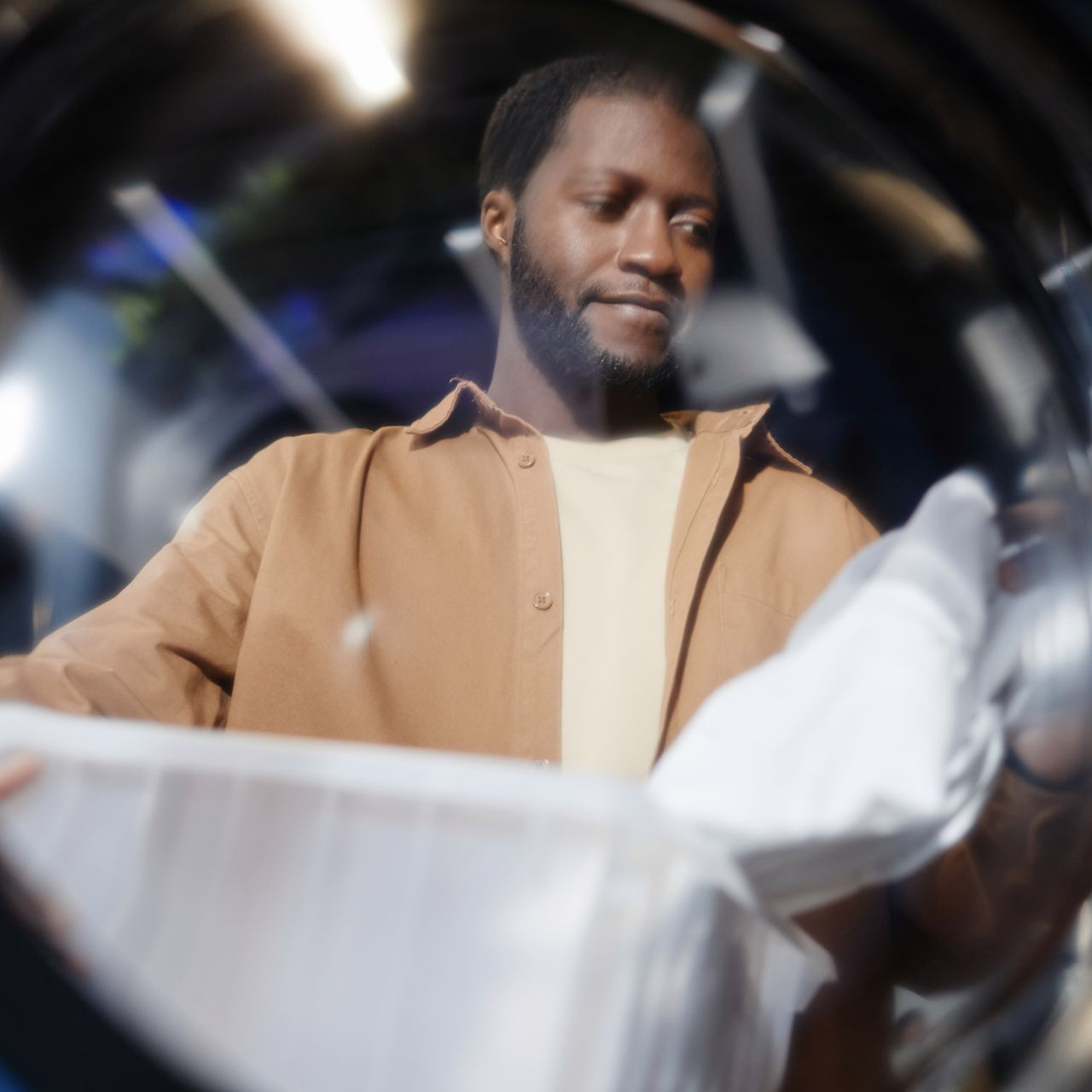 Man in brown shirt looking inside a dryer at a Fresh Suds Laundromat.