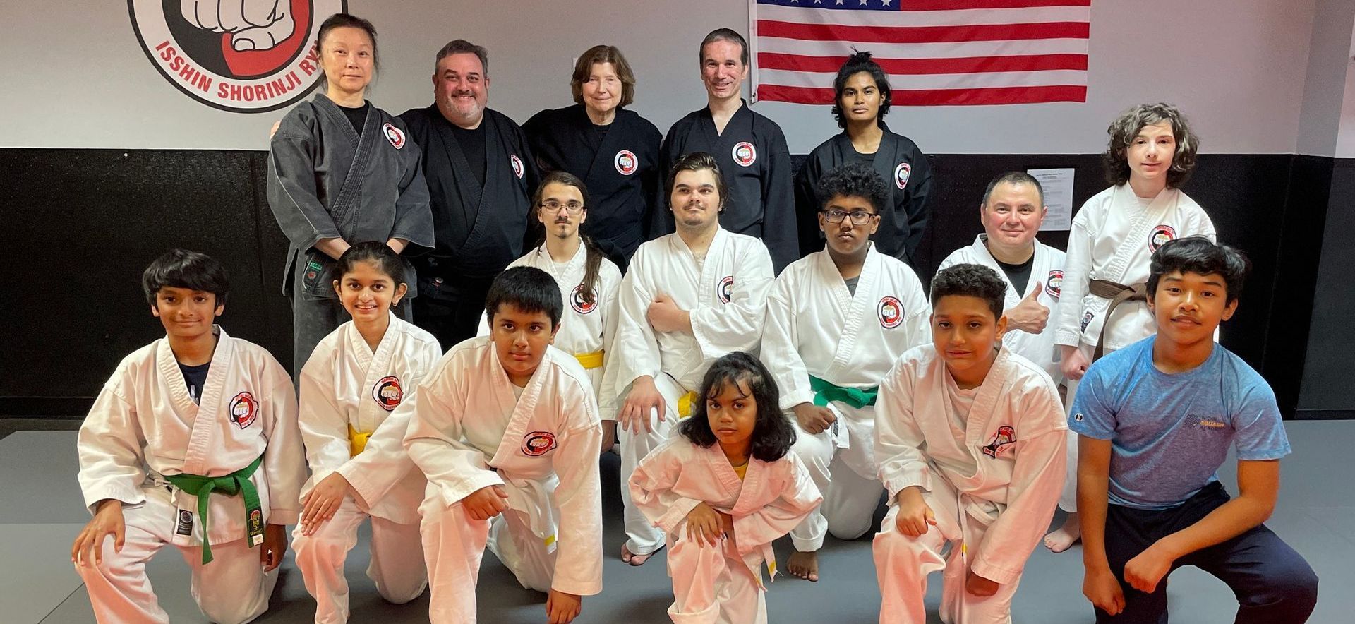 Two young boys in karate uniforms are standing next to each other in a dark room.
