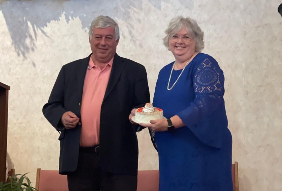 A man and a woman are standing next to each other holding a cake