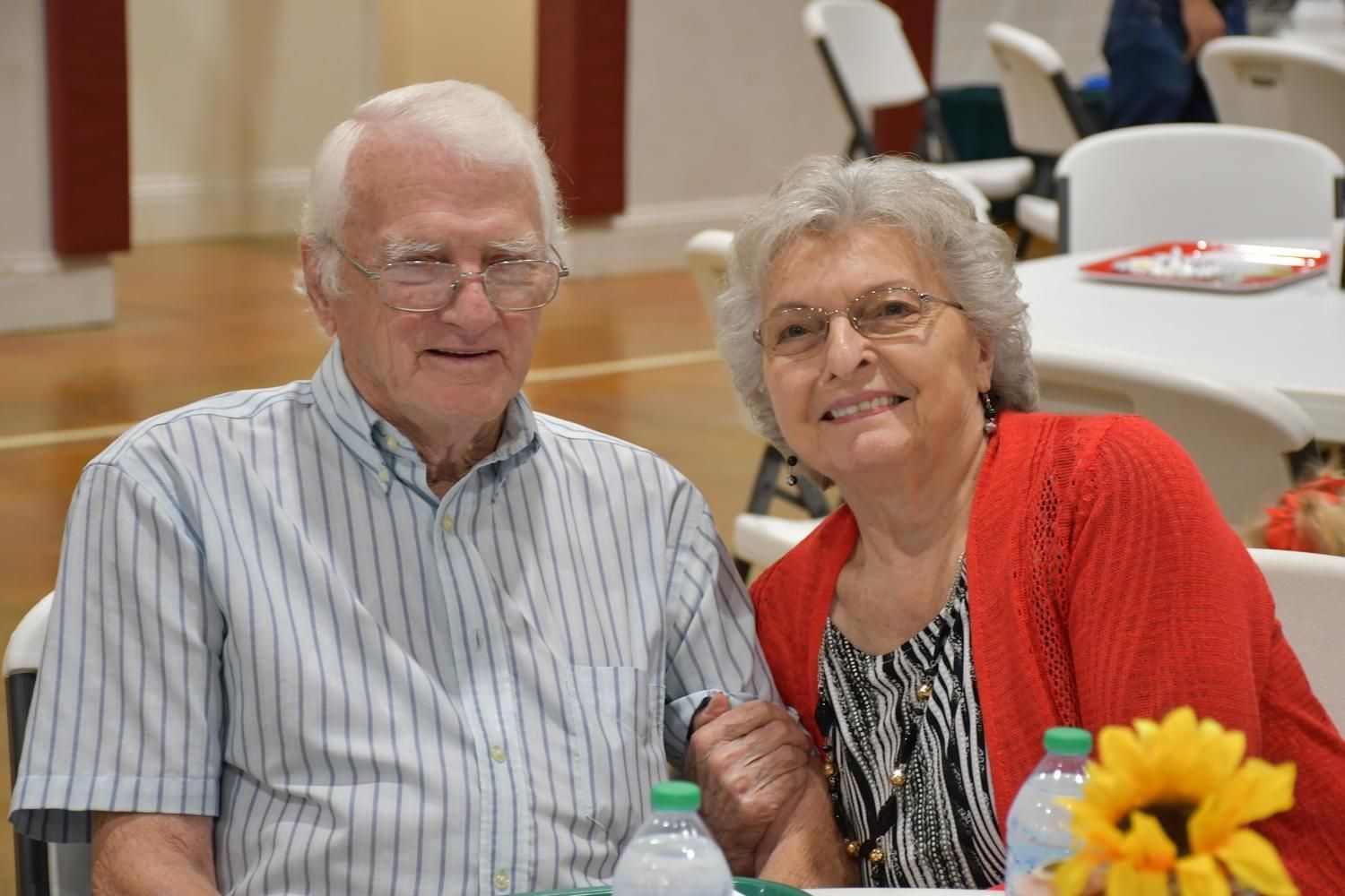 A man and a woman are posing for a picture while sitting at a table.