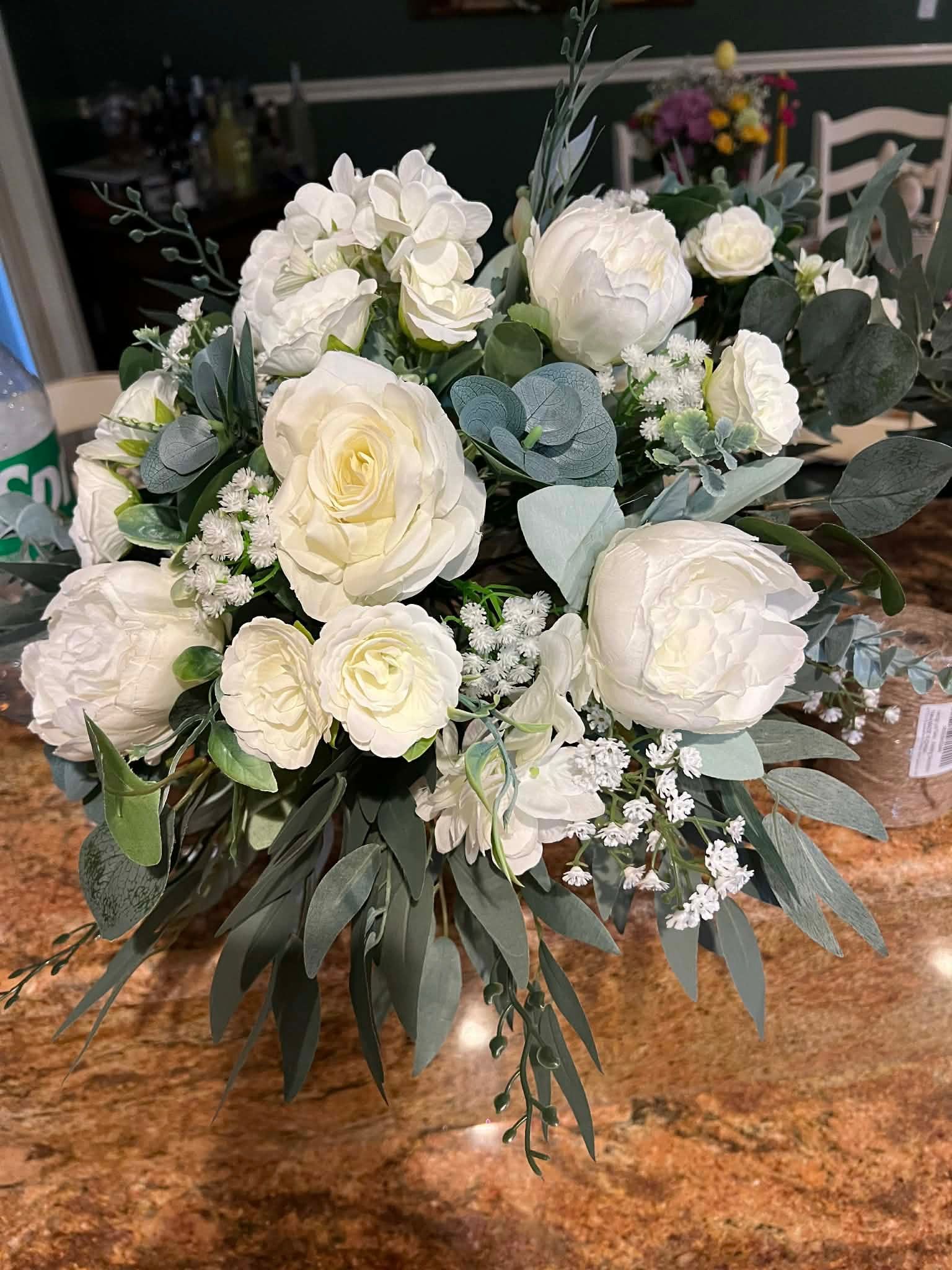 Champagne flutes arranged on a table, filled with bubbly liquid; white tablecloth, decorative urn, pink feathers.