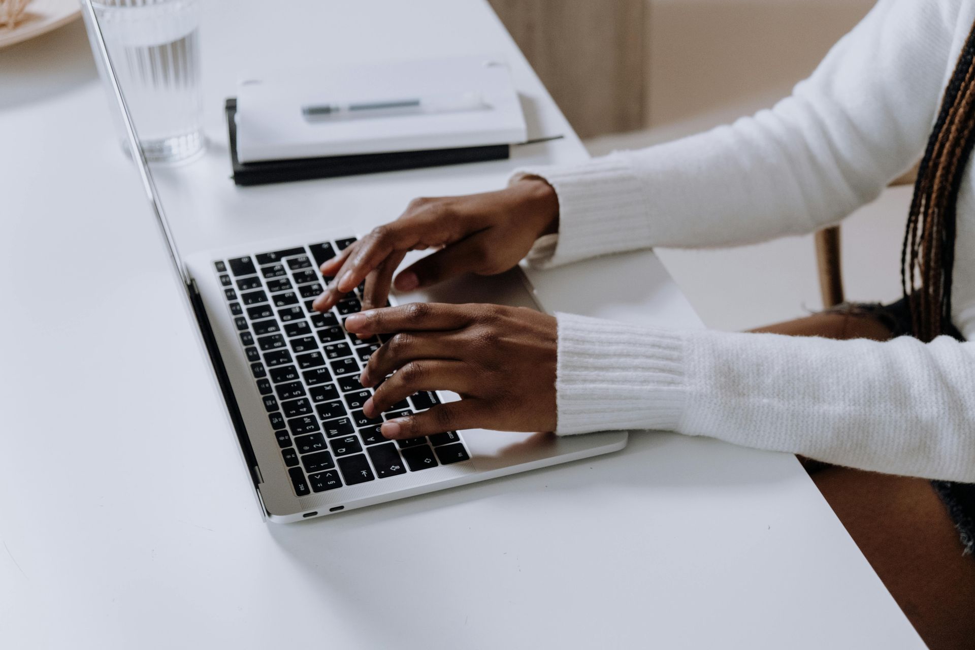 A woman is typing on a laptop computer at a desk.