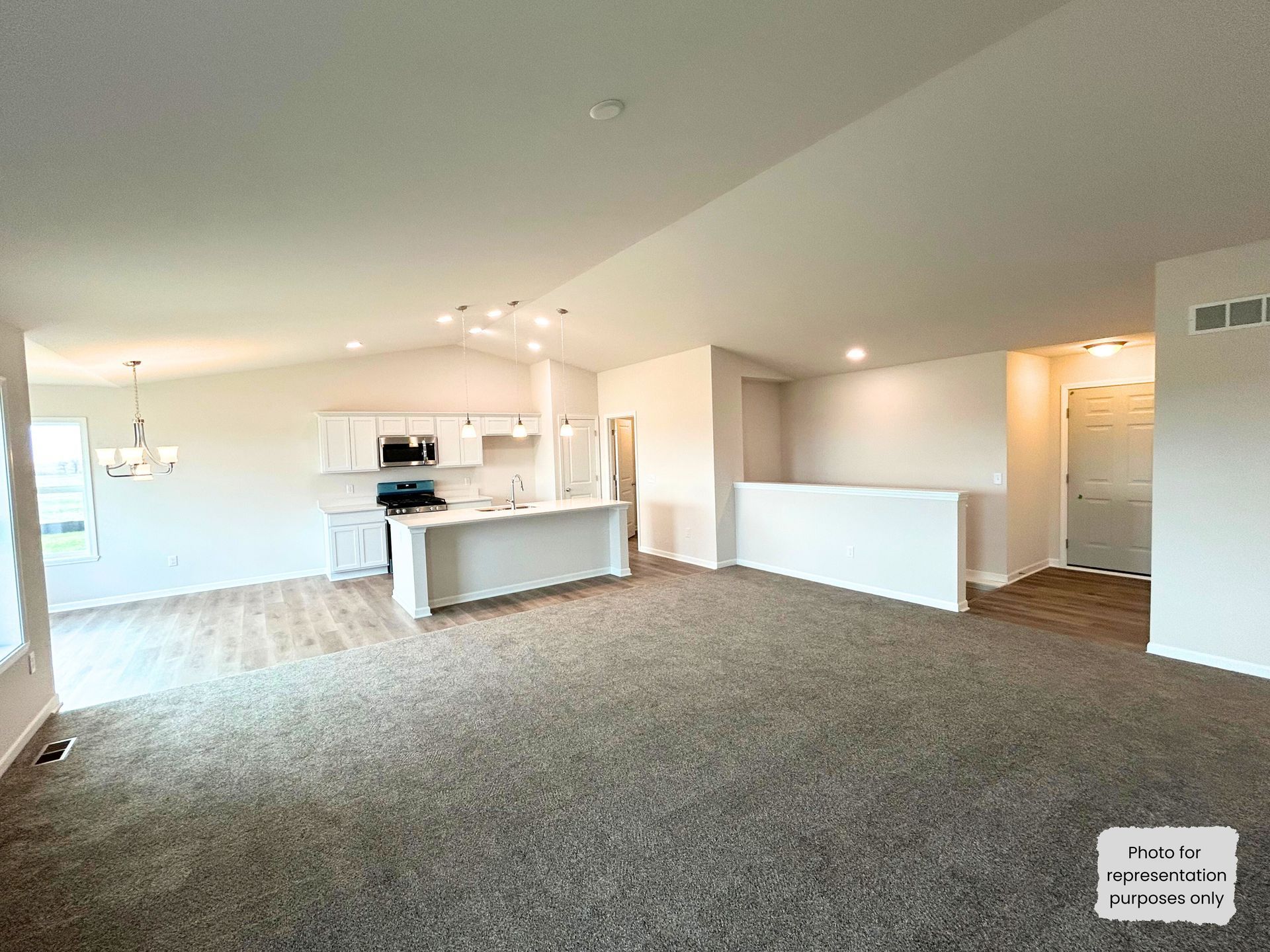 Interior of a modern house with open concept living and kitchen, neutral colors, carpeted floors.