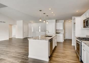 Open-concept kitchen with white cabinets, granite countertops, and stainless steel appliances.