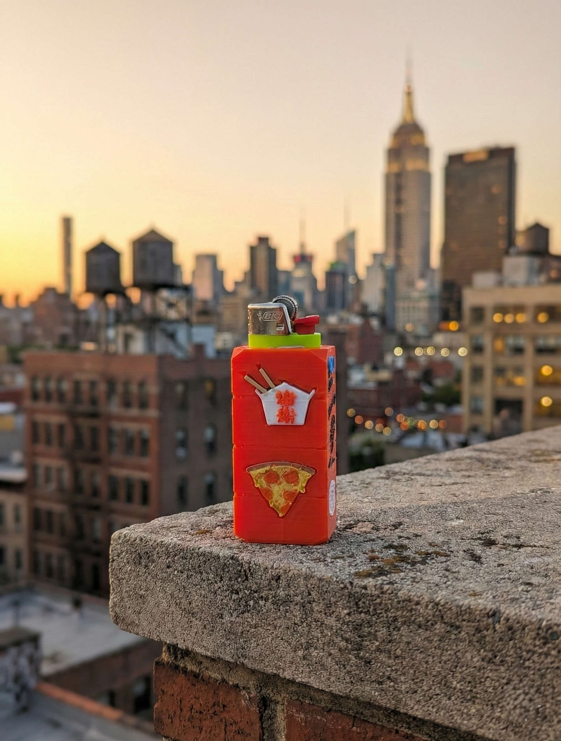 A red rectangular box with food and sneaker charms; brick background.