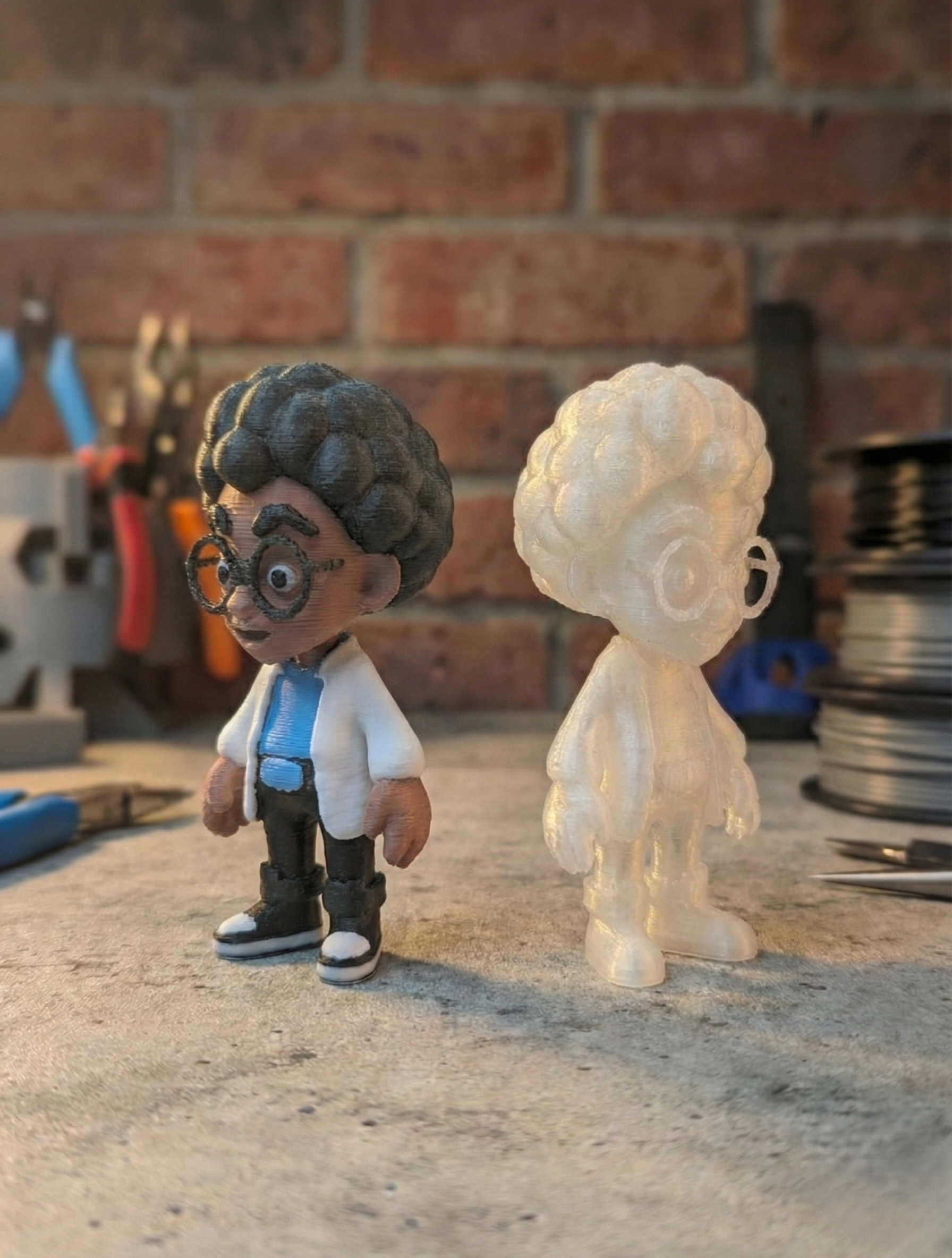 3D-printed figurine of a person wearing glasses and a lab coat next to a 3D-printed sign on a table.