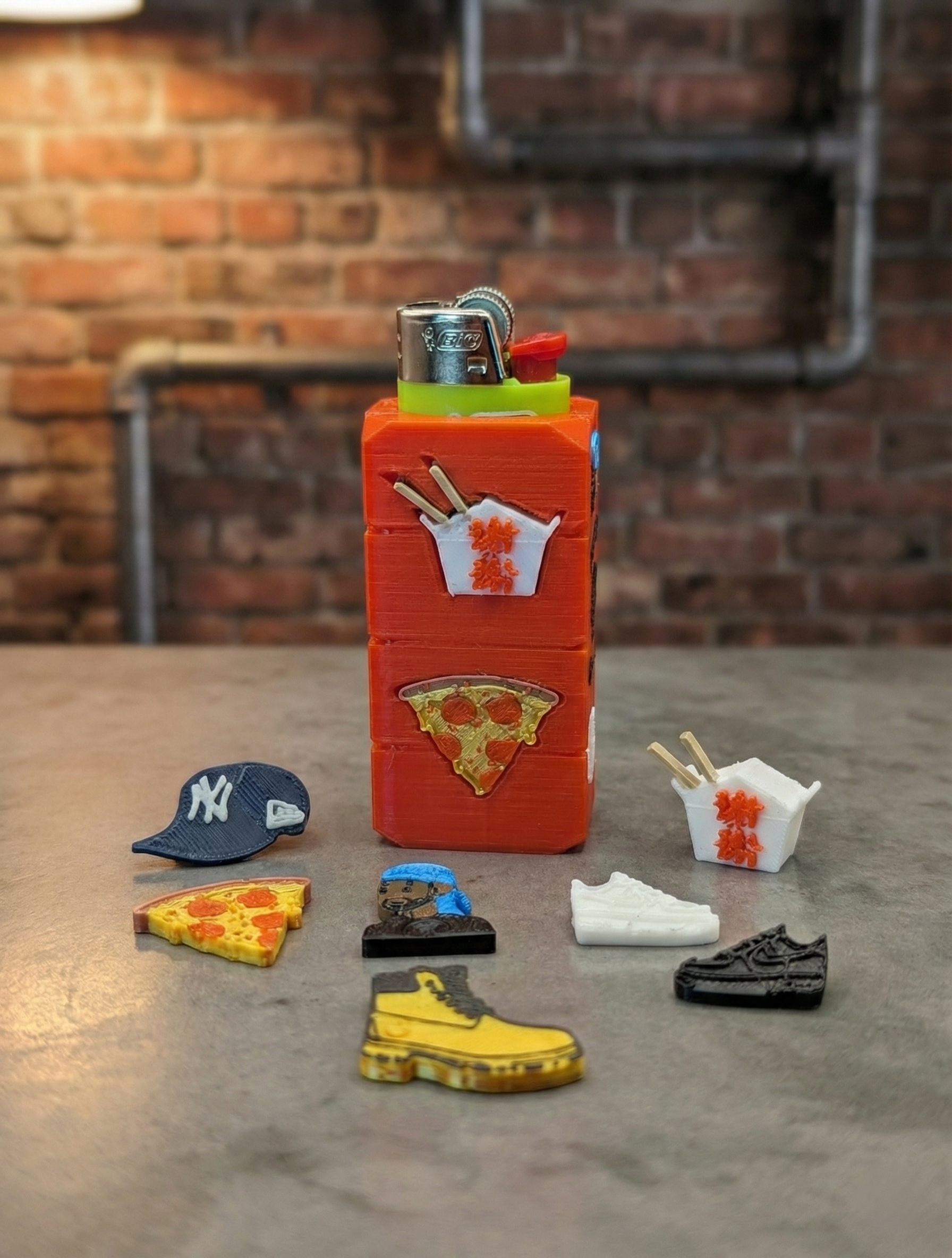 A red rectangular box with food and sneaker charms; brick background.