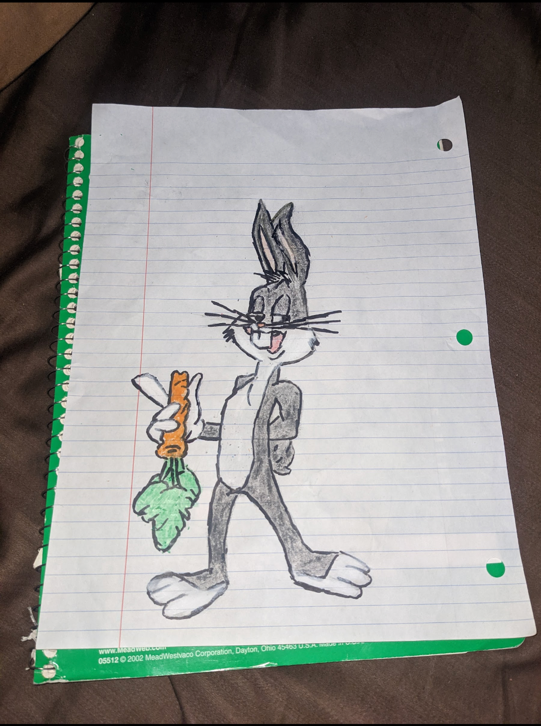 Bugs Bunny cartoon drawing holding a carrot, on lined paper with a green spiral notebook visible.