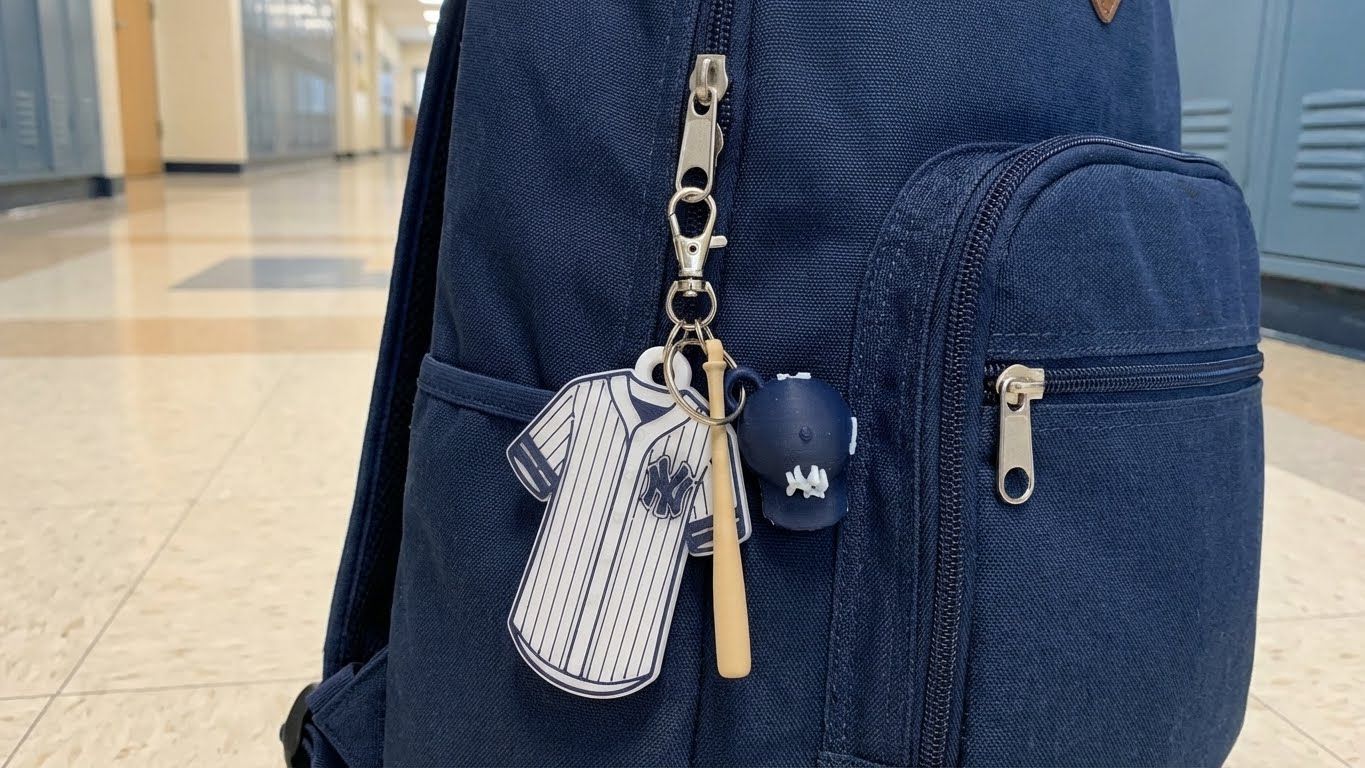 New York Yankees keychain, baseball, and glove on a wooden table, with city skyline in the background.