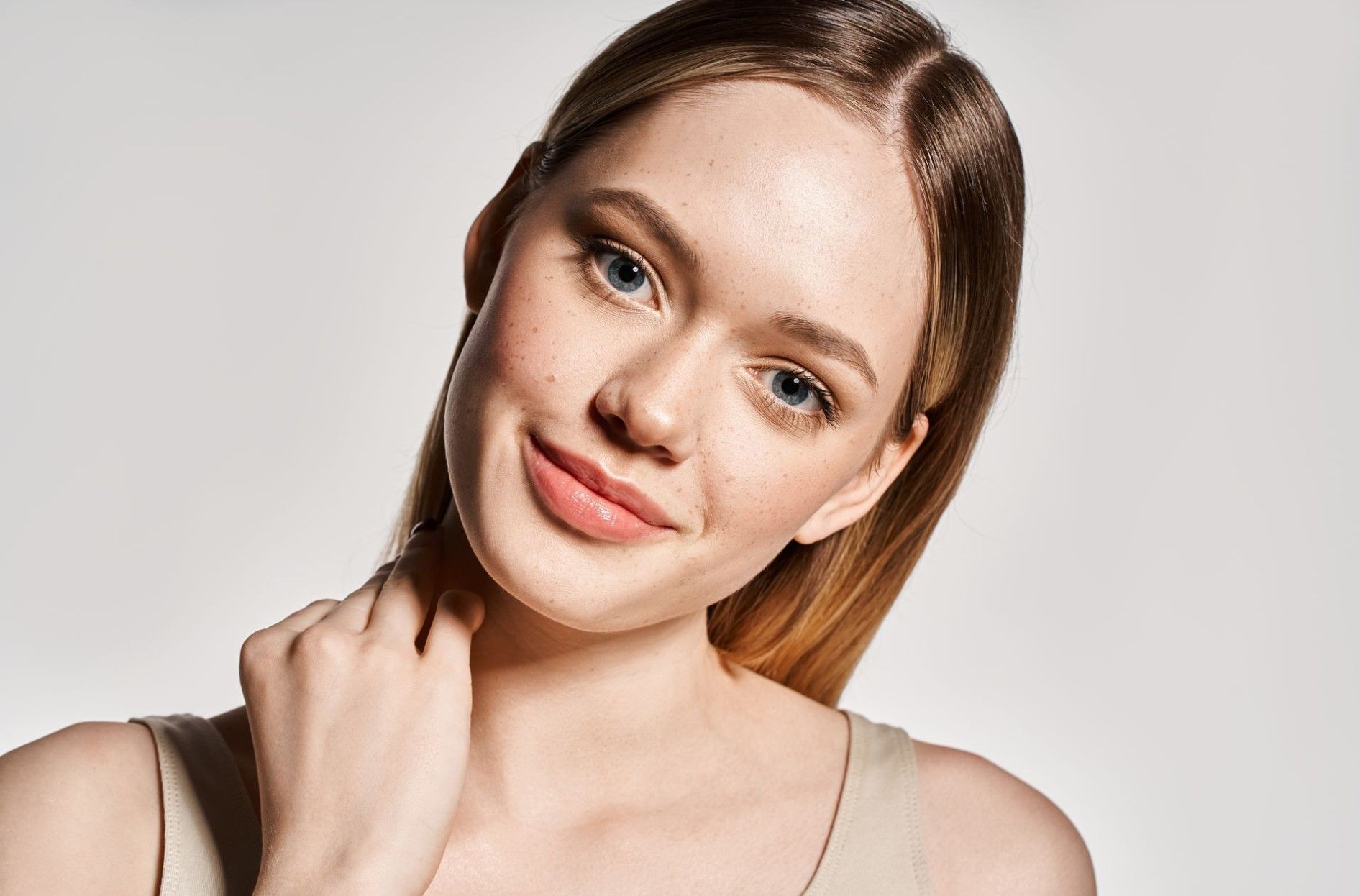 Close-up portrait of a smiling woman with light brown hair against a plain background