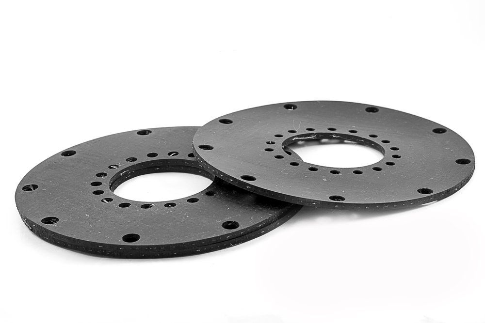 Zwei schwarze Gummiringe mit Löchern auf einer weißen Fläche.