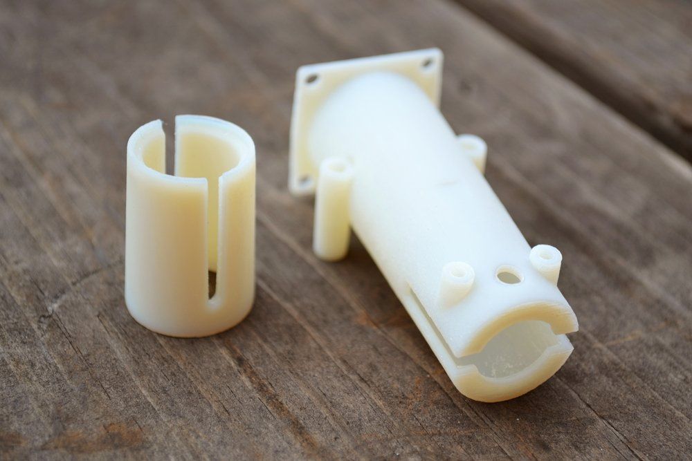 Auf einem Holztisch liegen zwei weiße Plastikteile.