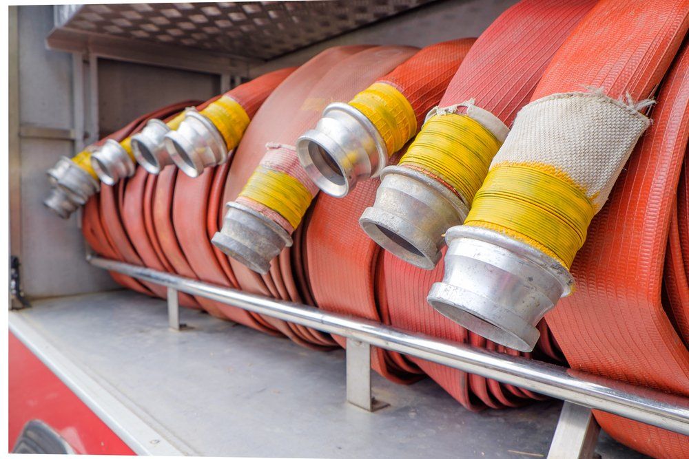 Mehrere Feuerwehrschläuche sind auf einem Gestell aufgereiht.
