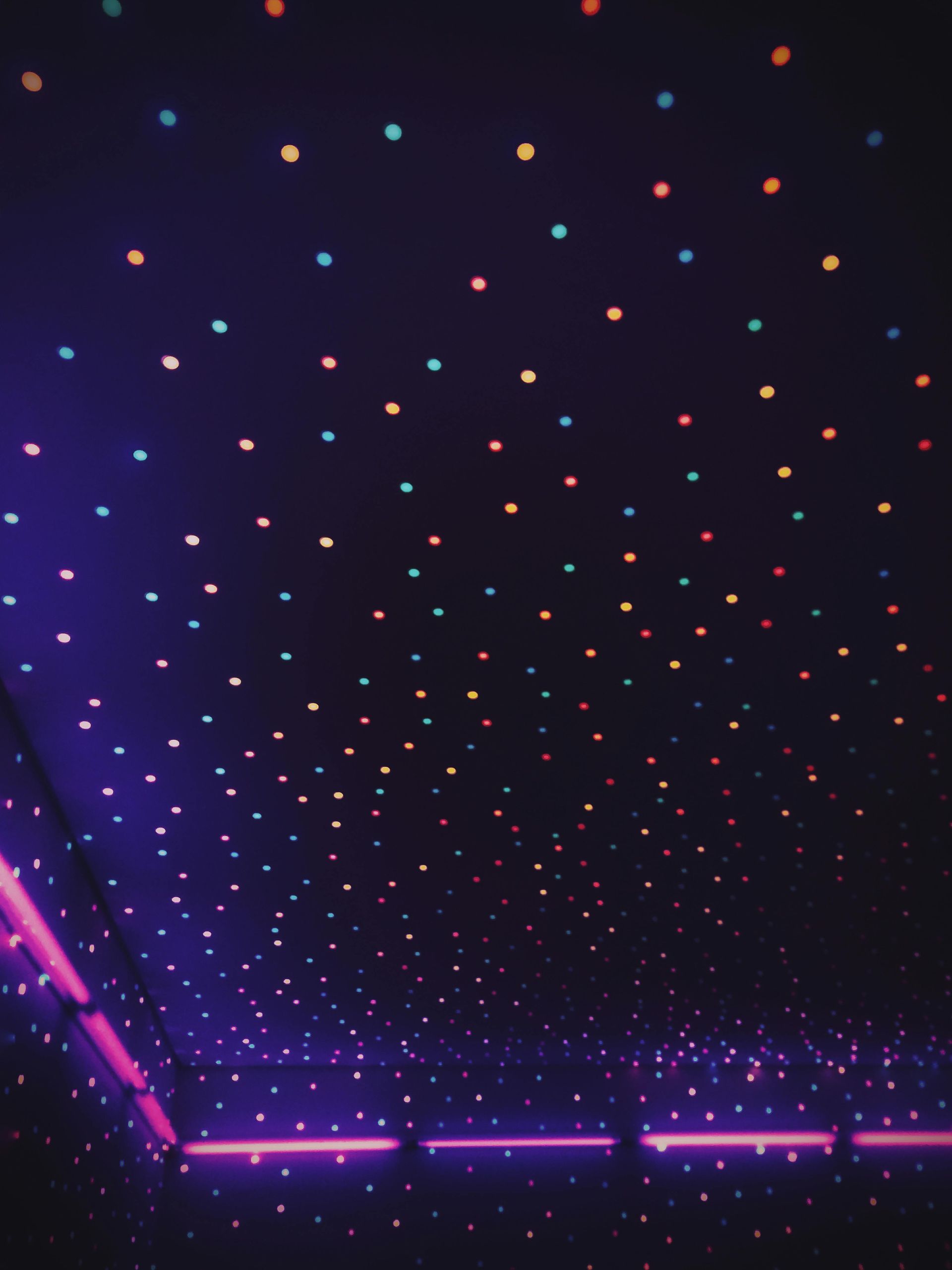 Purple-lit room ceiling with a constellation of colorful star-shaped lights, and neon pink lines along the walls.