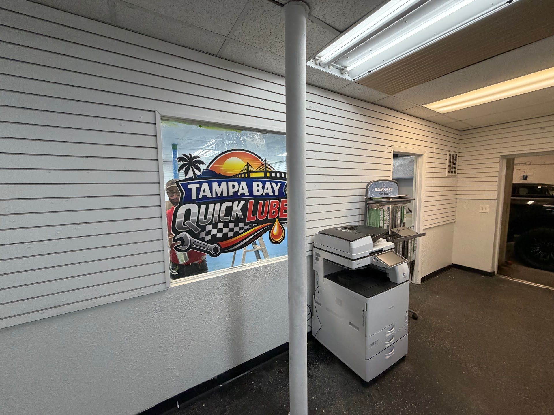 Interior of a Tampa Bay Quick Lube shop. Printer, window sign, and open doorway. | Tampa Bay Quick Lube