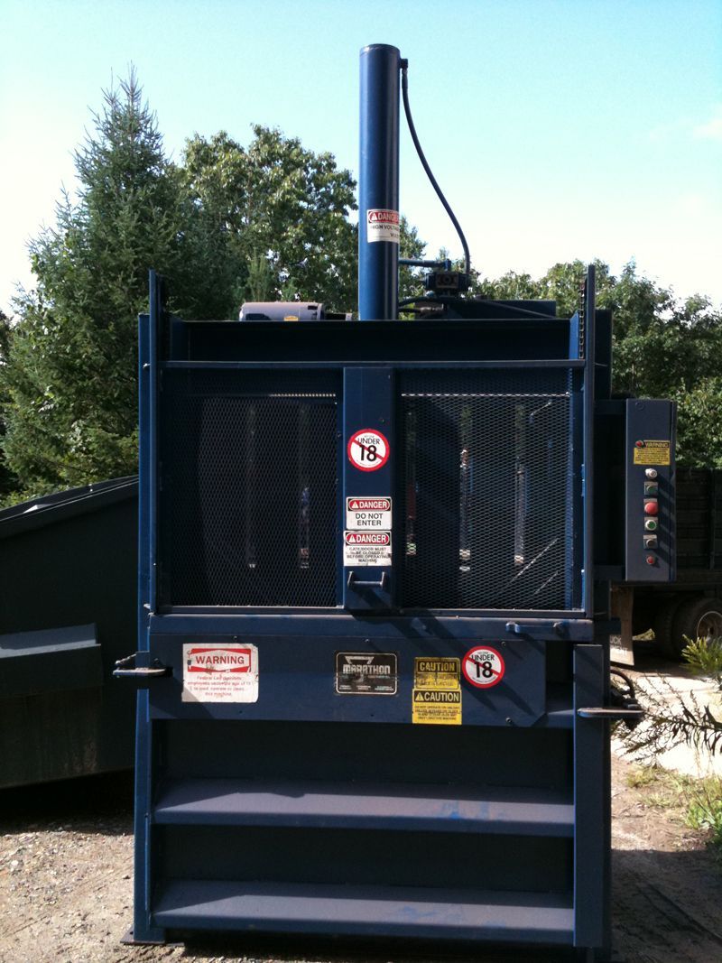 Blue industrial trash compactor machine, outside.