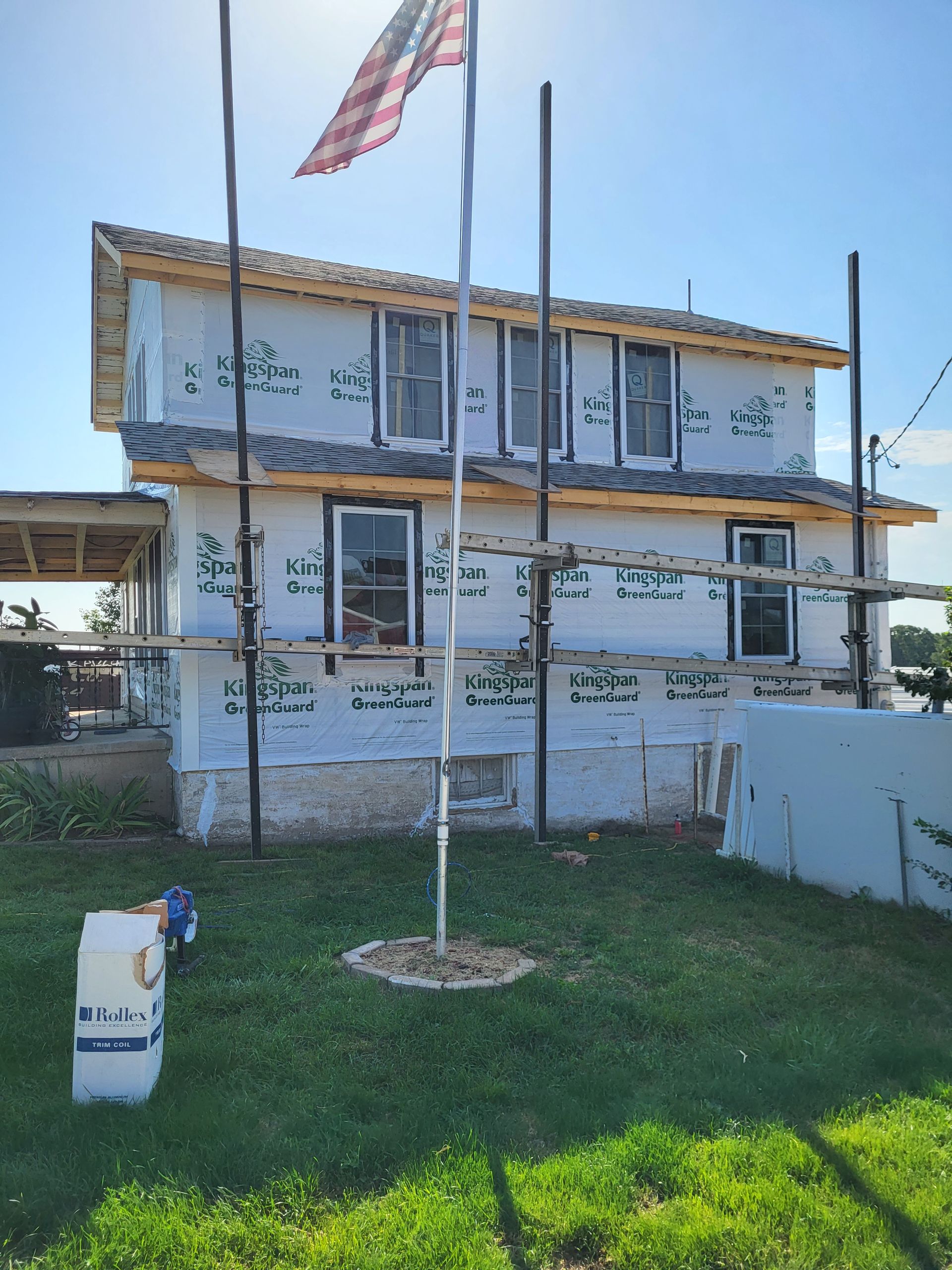 A house under construction with a flag flying in front of it.
