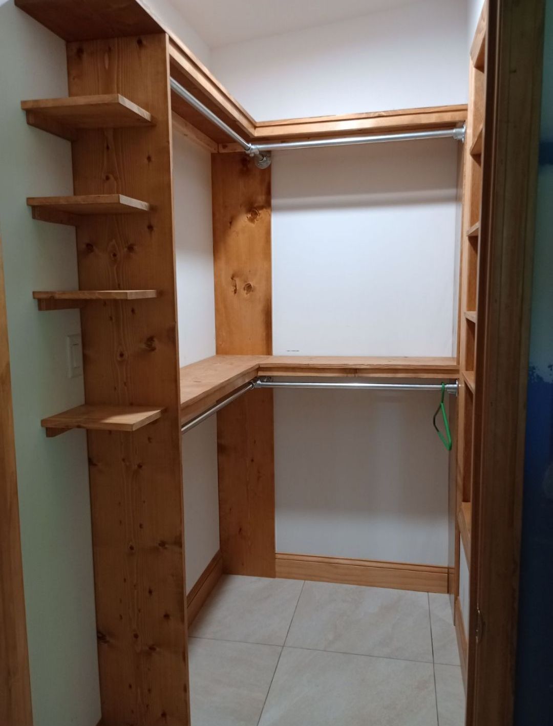 A walk in closet with wooden shelves and clothes racks