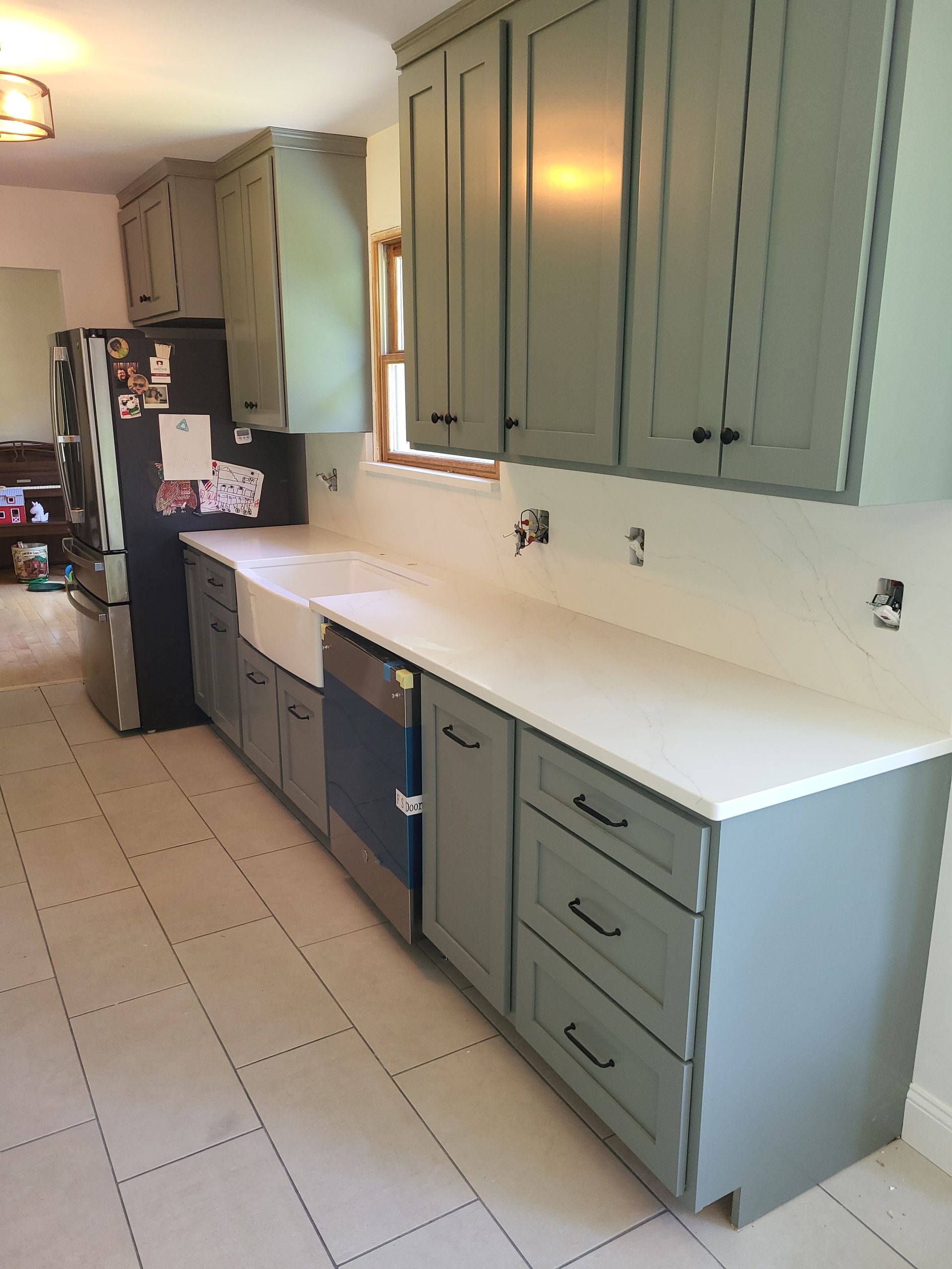 A kitchen with gray cabinets and white counter tops
