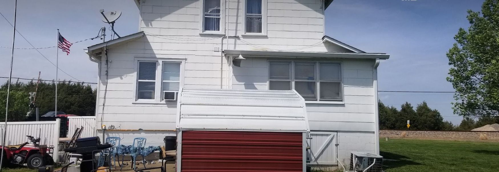 A white house with a red garage door and an american flag on top of it.