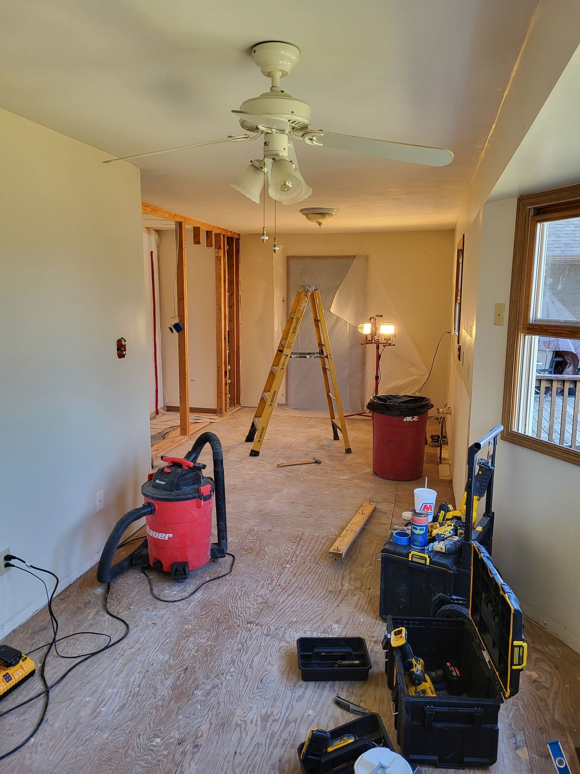 A living room is being remodeled with a ceiling fan and a vacuum cleaner.