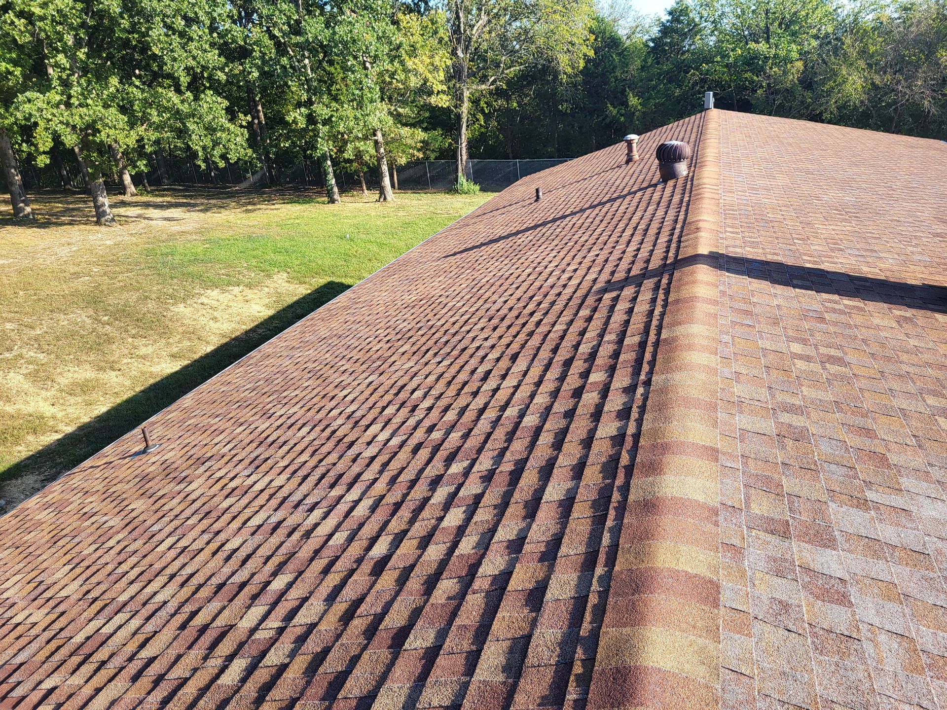 A roof with a lot of shingles on it and trees in the background.
