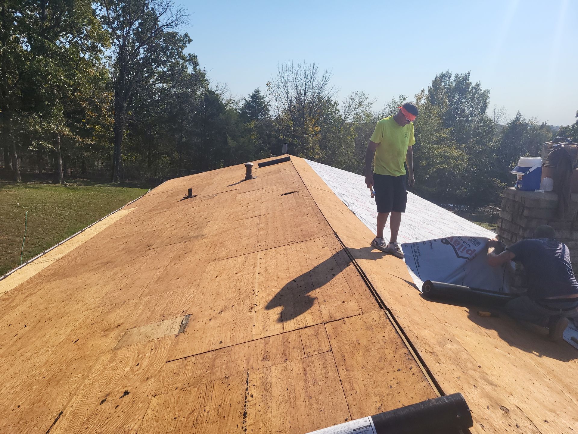 A man is standing on top of a wooden roof.