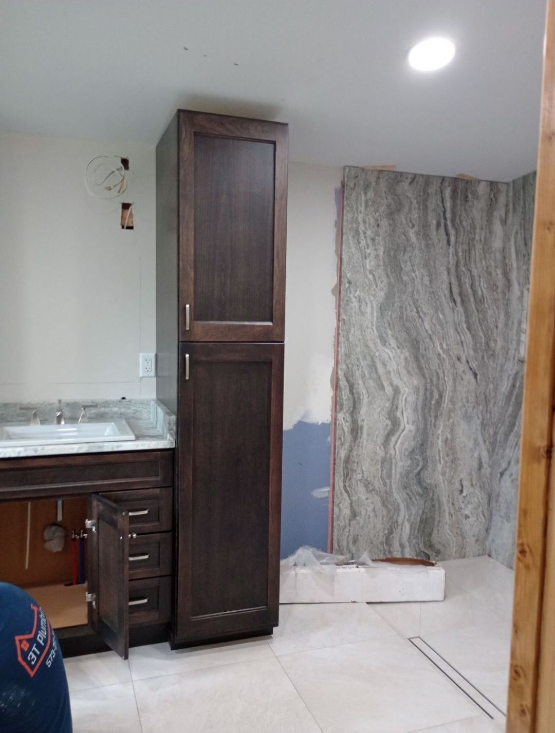 A bathroom with a sink , cabinets , and a marble wall.