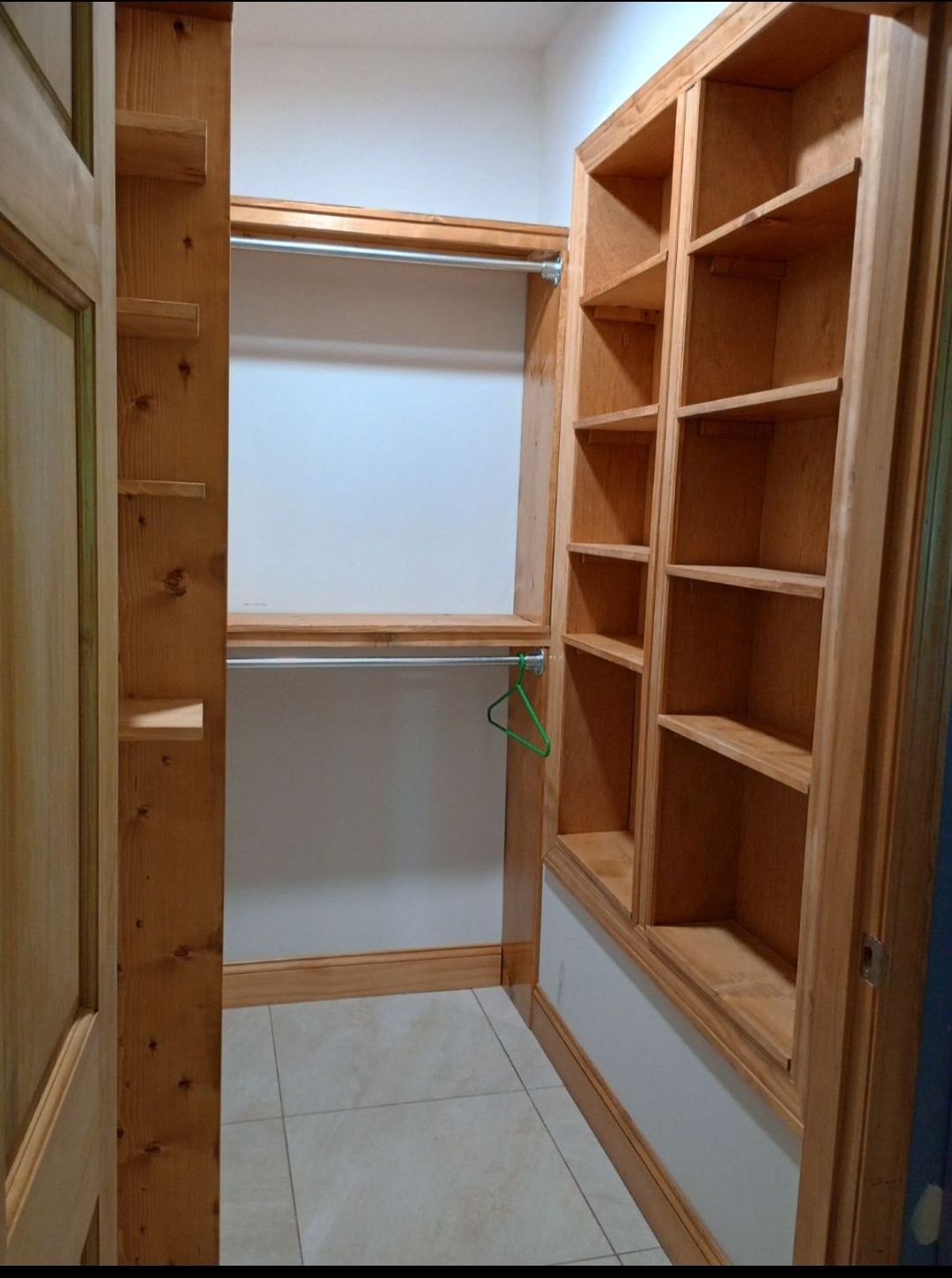 A walk in closet with wooden shelves and a hanger