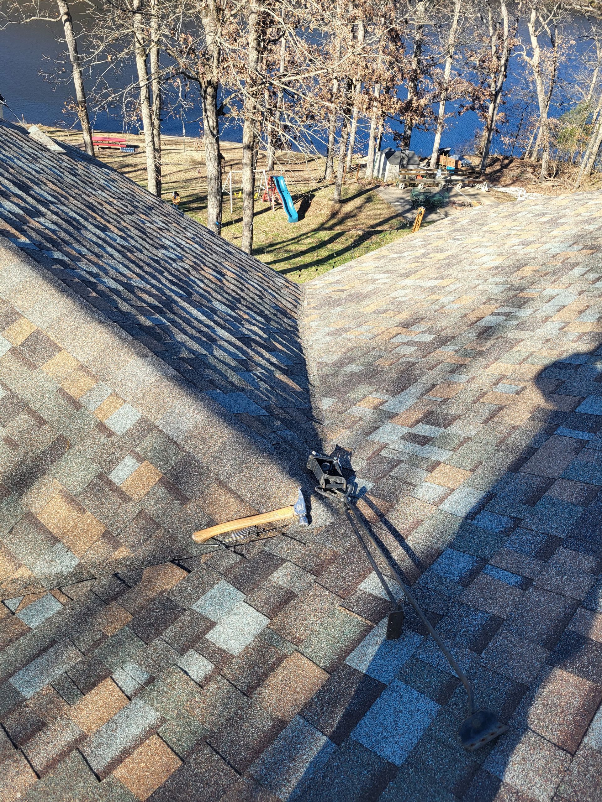A roof with a hammer on it and trees in the background.