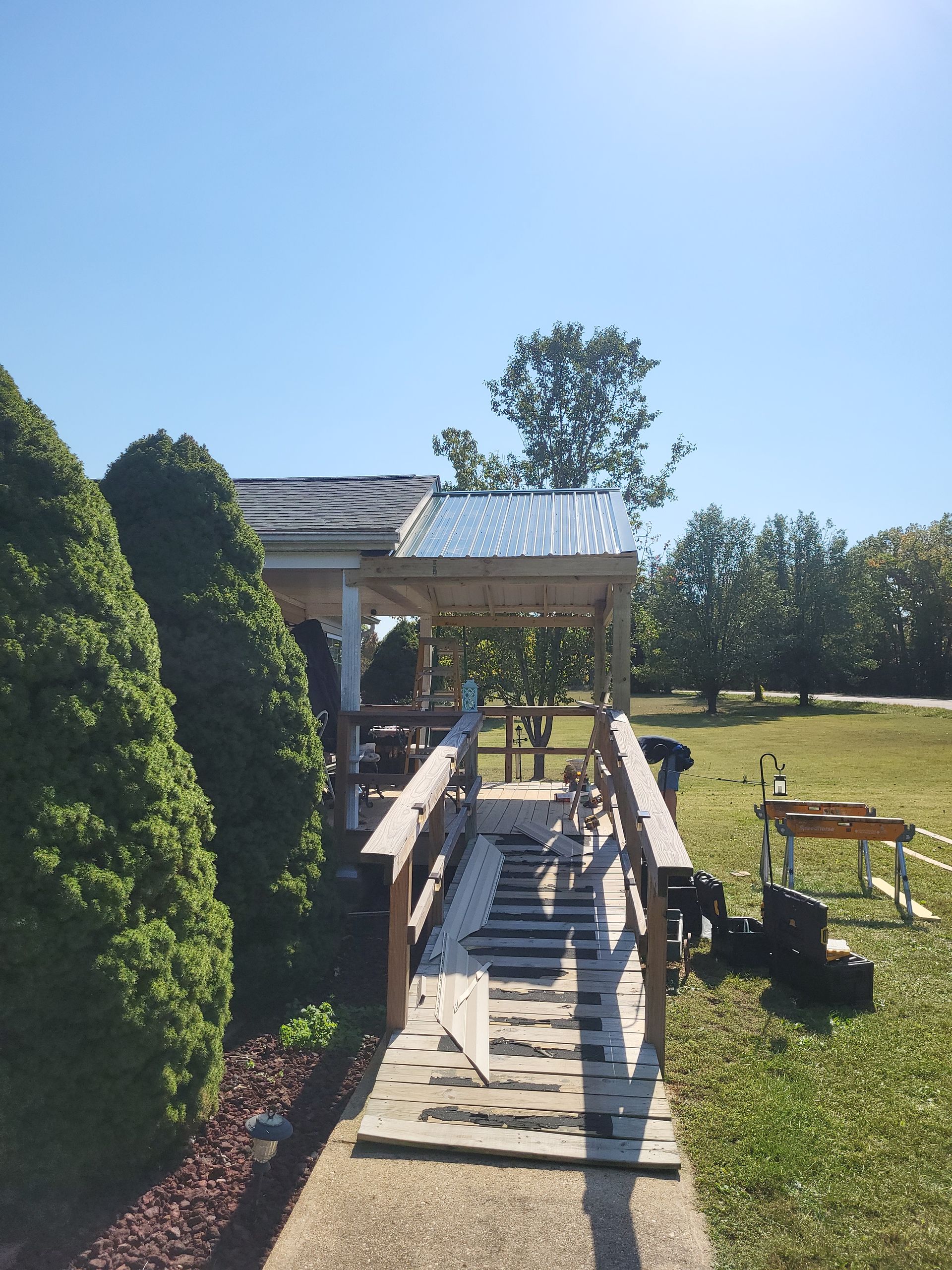 A wooden walkway leading to a house with a metal roof