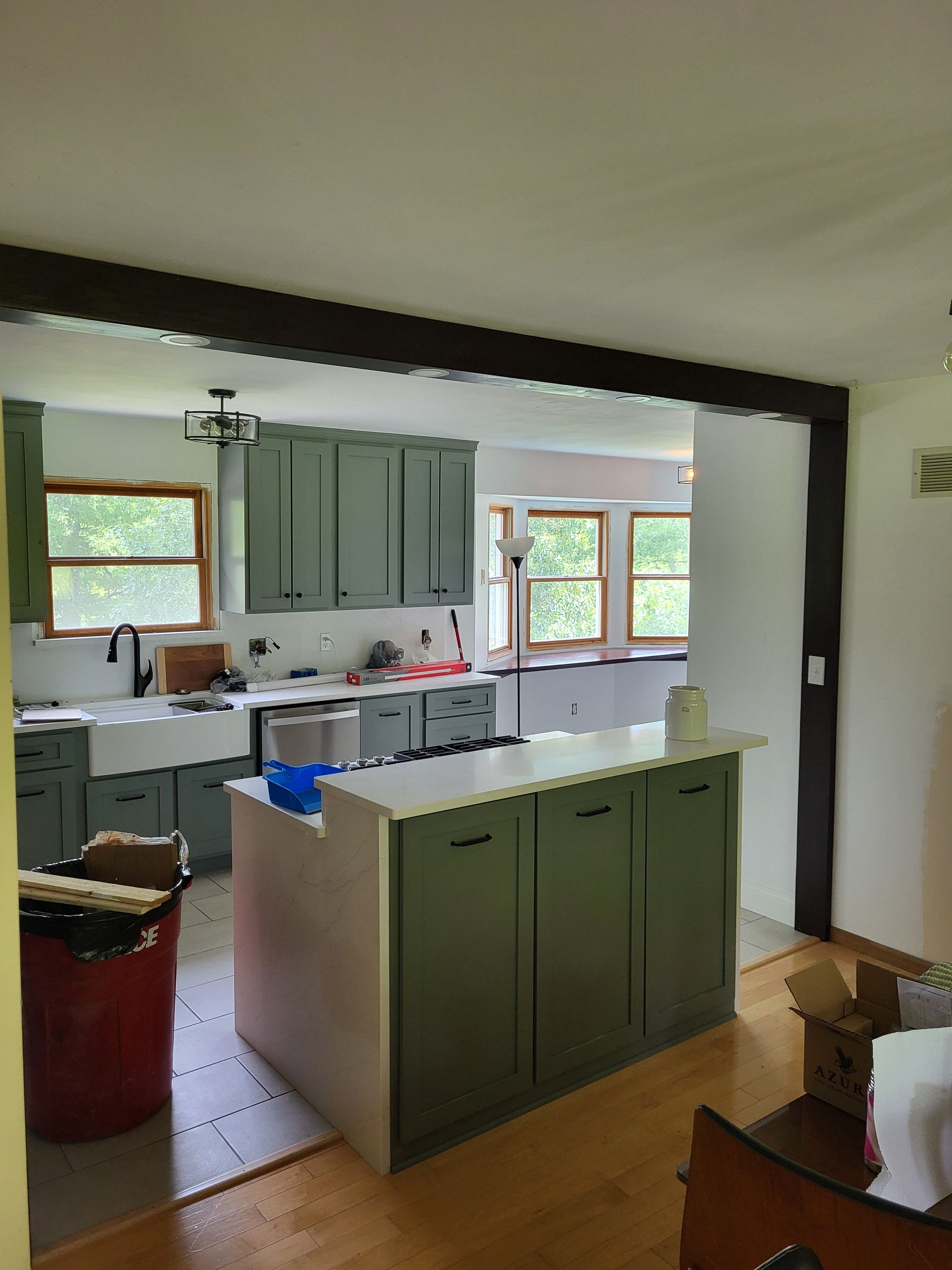 A kitchen with green cabinets and white counter tops