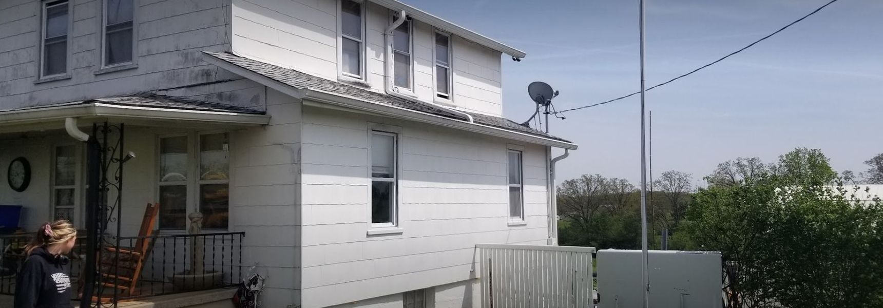 A man is standing in front of a white house.