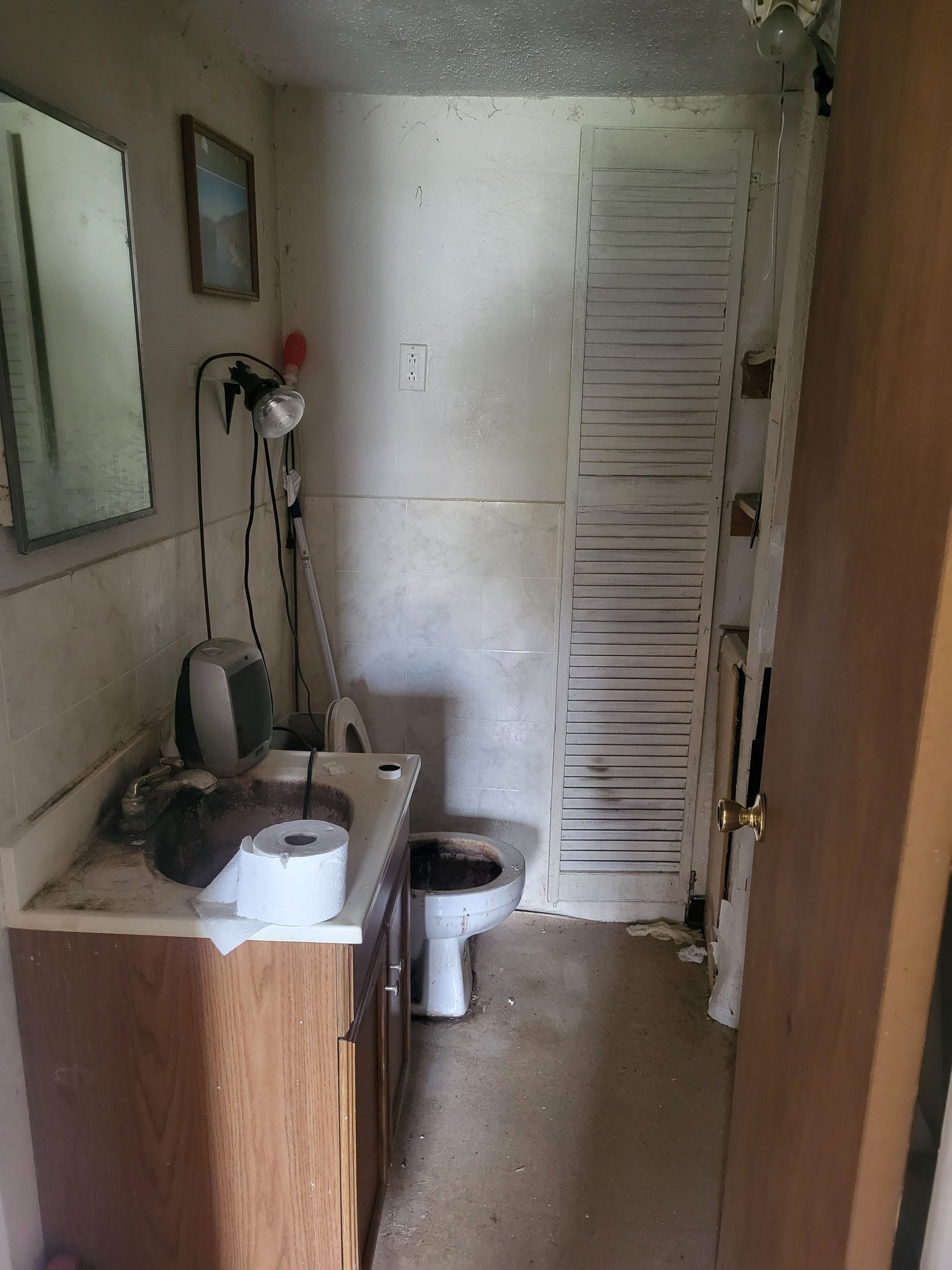 A bathroom with a toilet , sink and mirror.