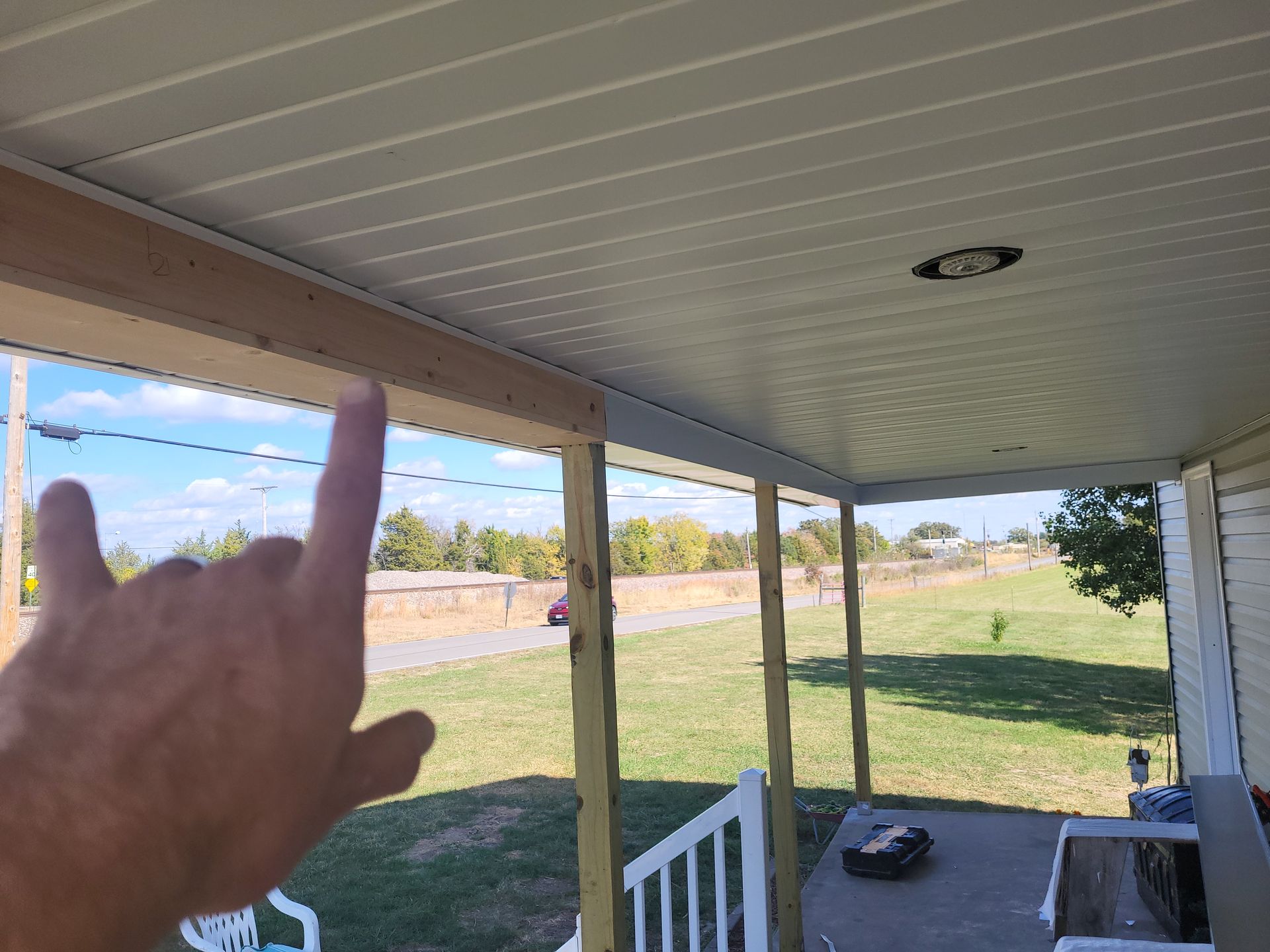 A person is pointing at the ceiling of a porch.