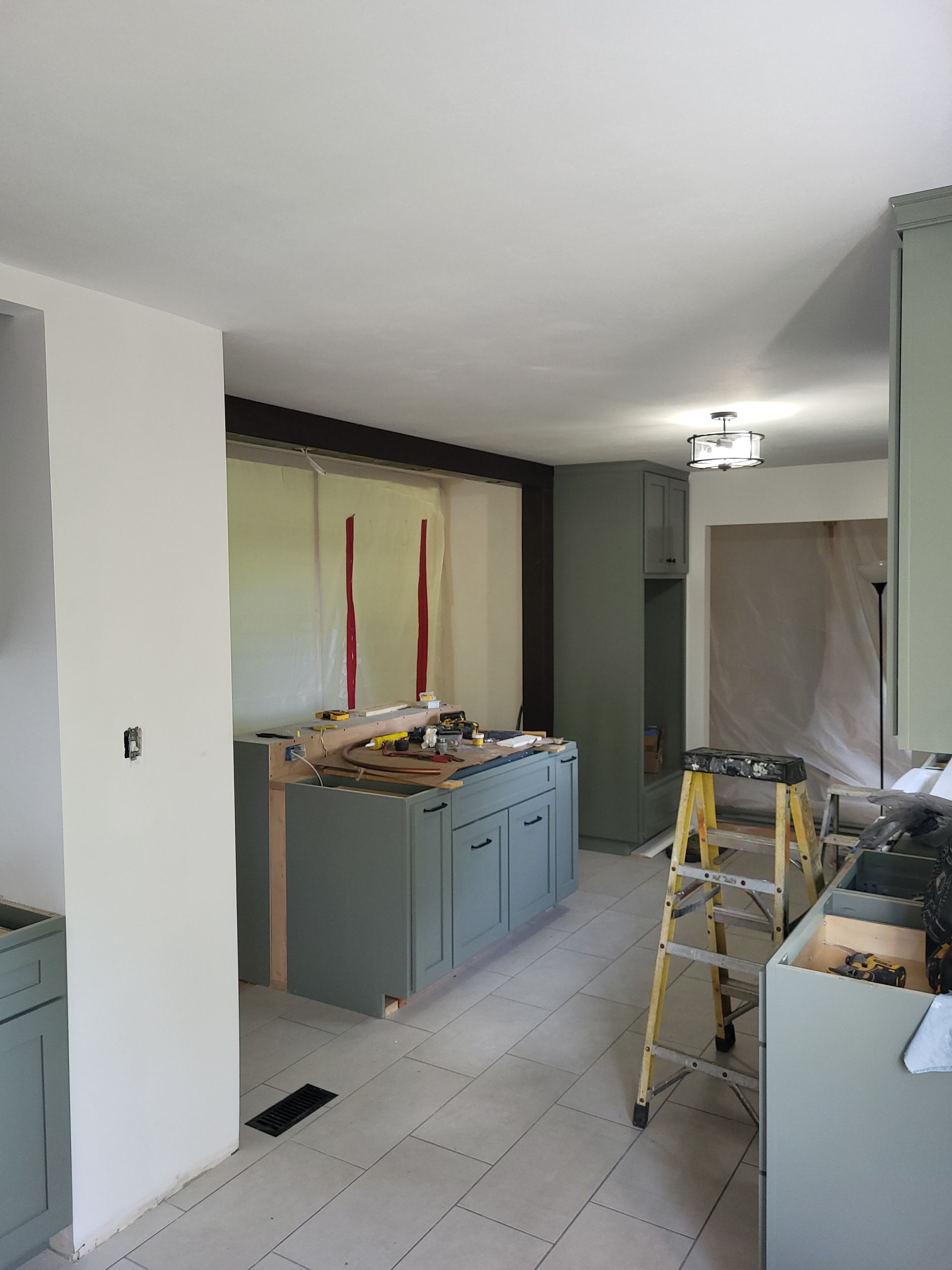 A kitchen under construction with a ladder in the middle of the room.