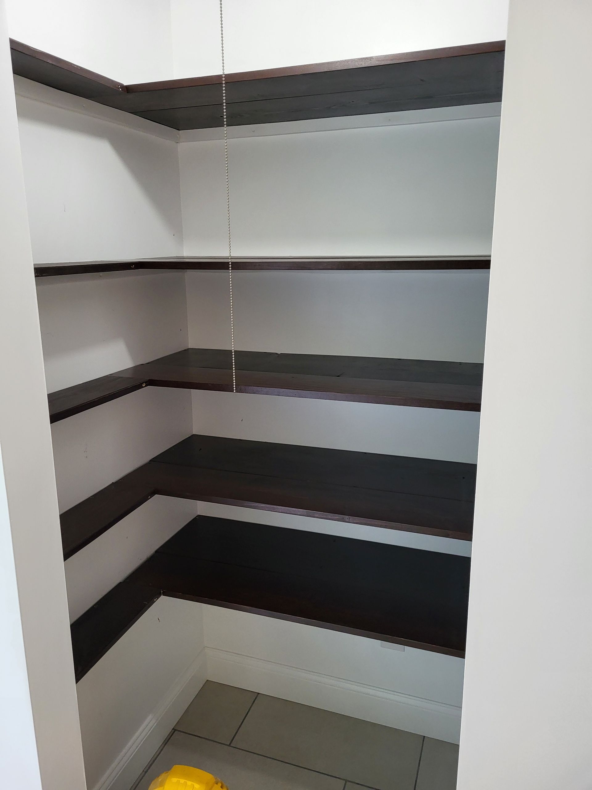 A closet with a lot of shelves and a yellow ball on the floor.