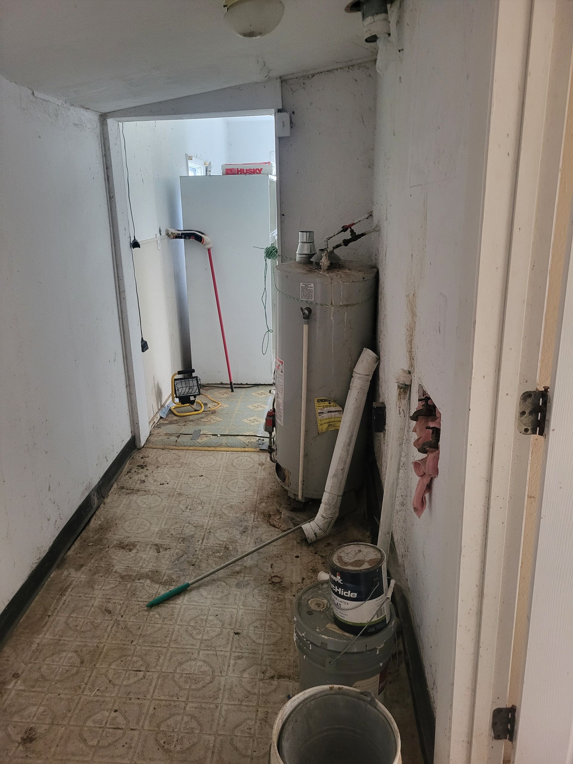 A room with a water heater and a refrigerator in it.