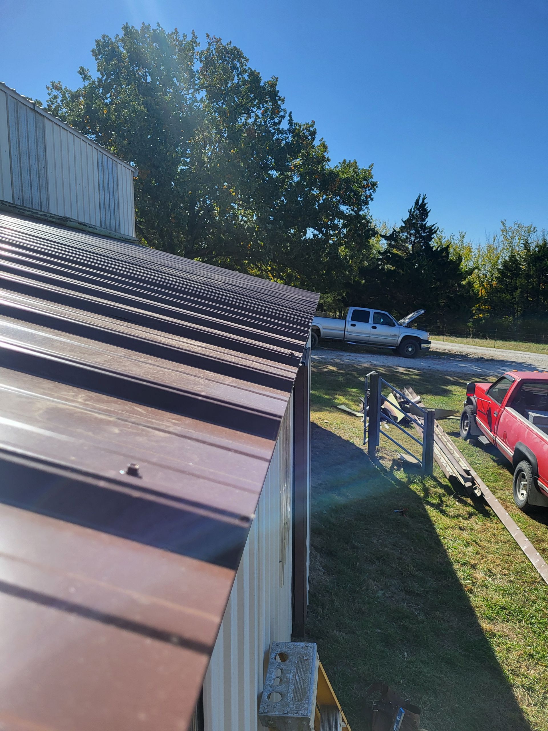 A red truck is parked in front of a building with a metal roof.