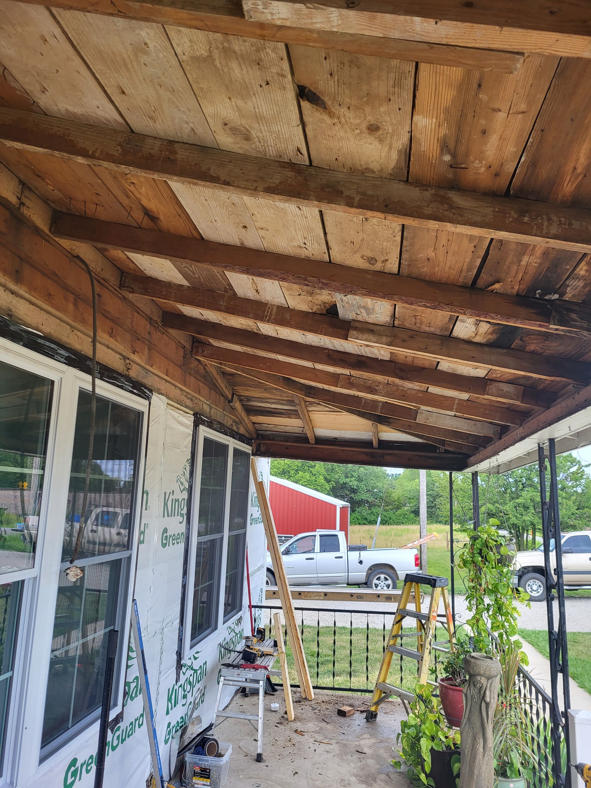 A porch with a wooden ceiling and a ladder.