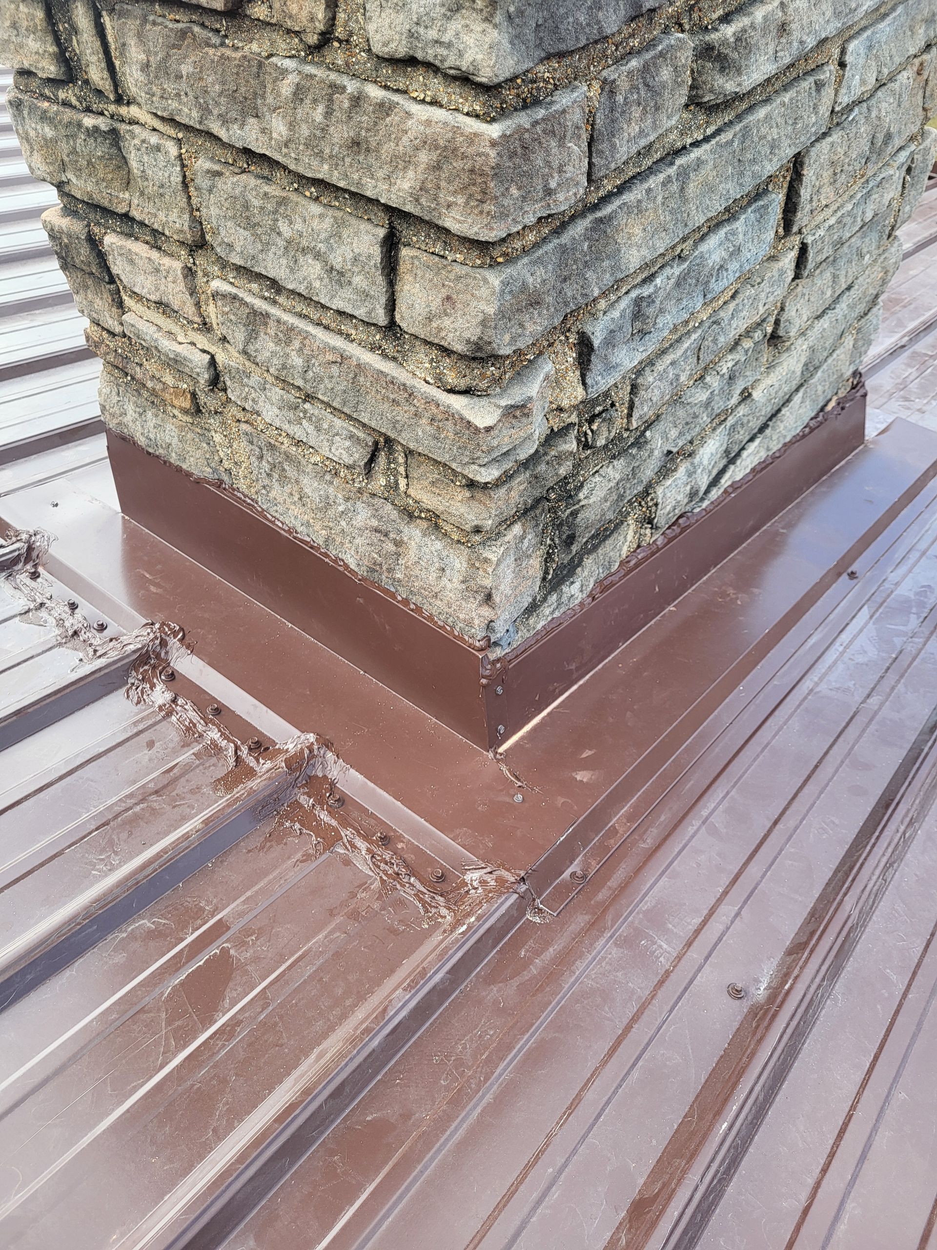 A brick chimney is sitting on top of a metal roof.