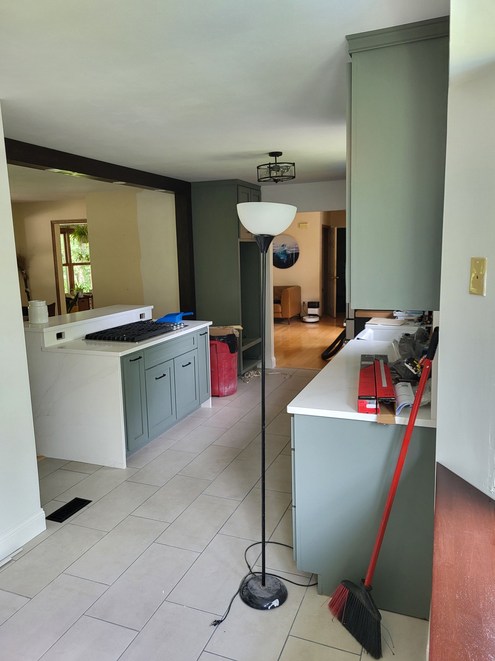 A kitchen with a lamp and a broom on the floor.