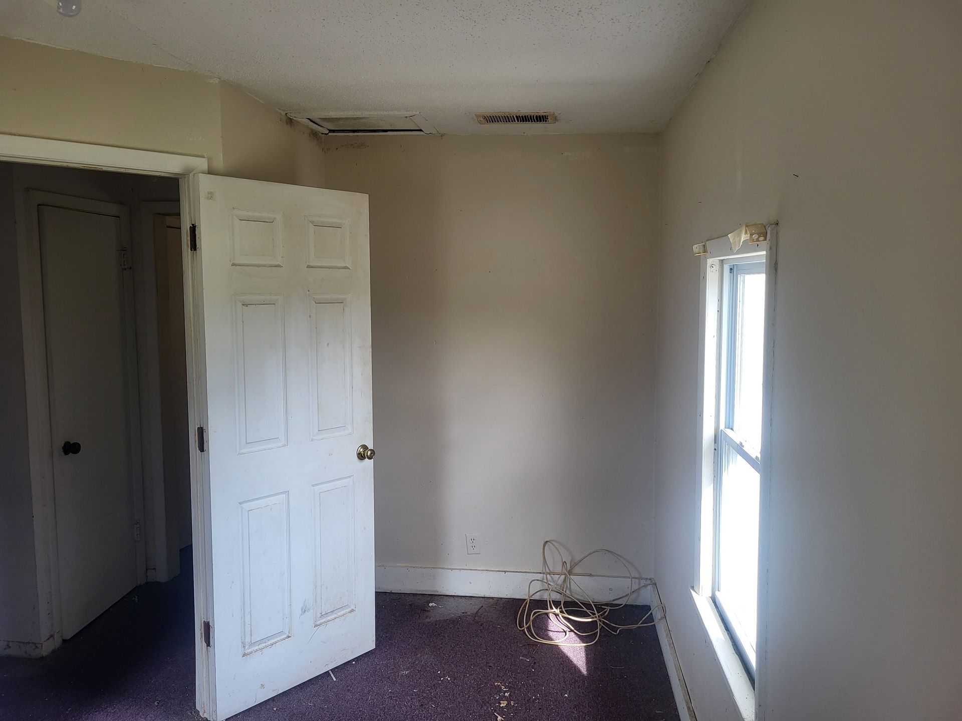 An empty room with a door open and a window.