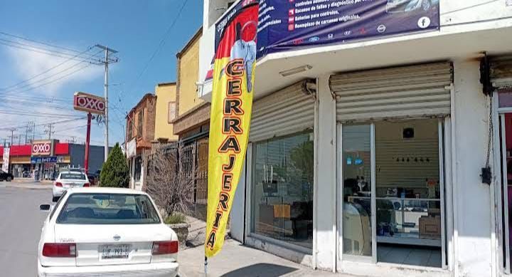 Vista exterior de una cerrajería con una bandera amarilla que dice 